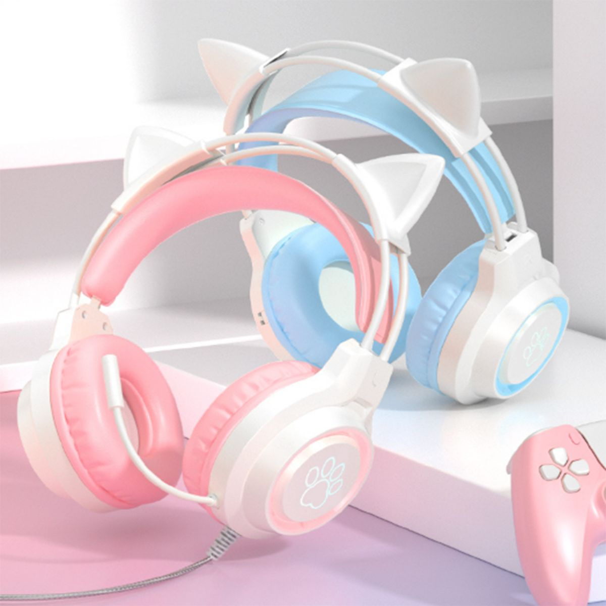 Rosa und blaue Katzenohr-Kopfhörer. Ein rosa und ein blaues Paar werden gezeigt. Ein rosa Gamecontroller.