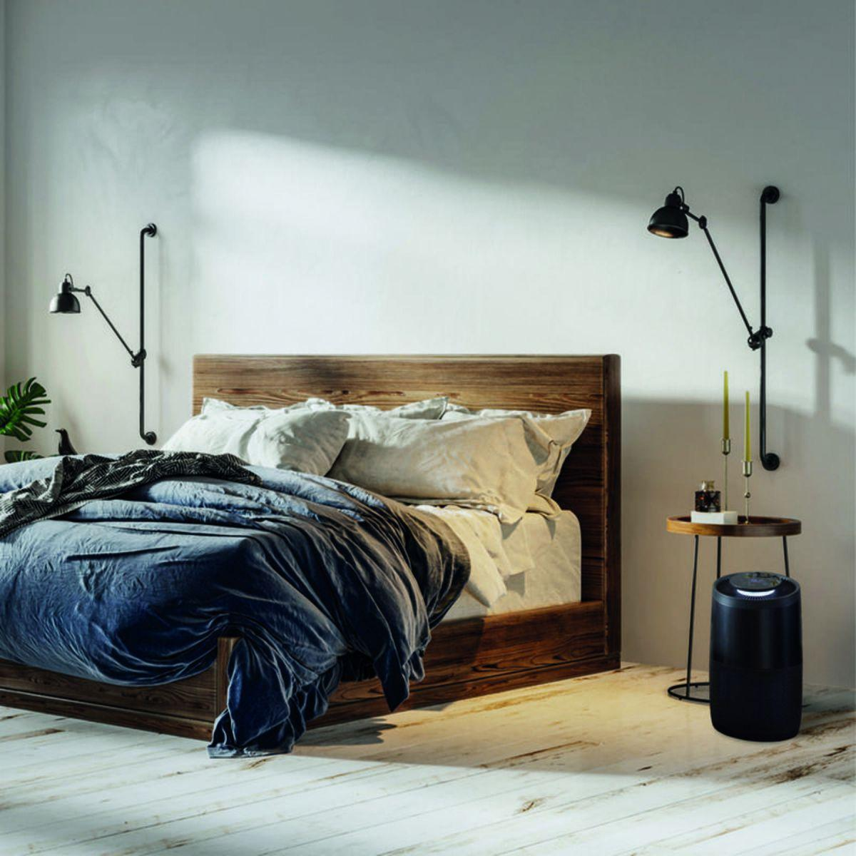 Scena di camera da letto con letto, lampade e purificatore d'aria nero.