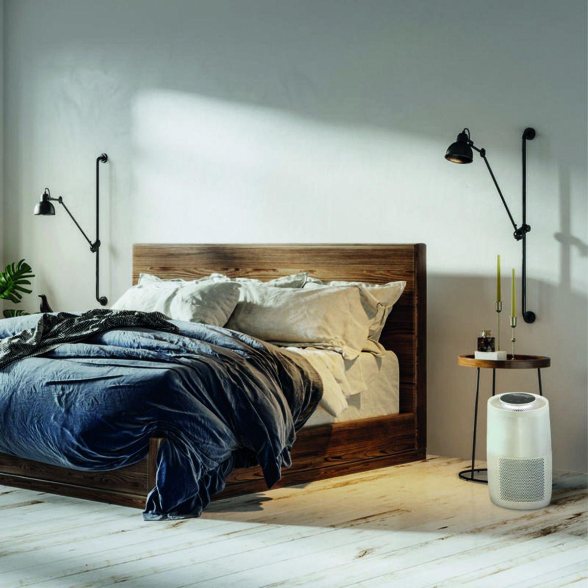 Ein Schlafzimmer mit Holzbett, zwei Lampen und einem weißen Luftreiniger.