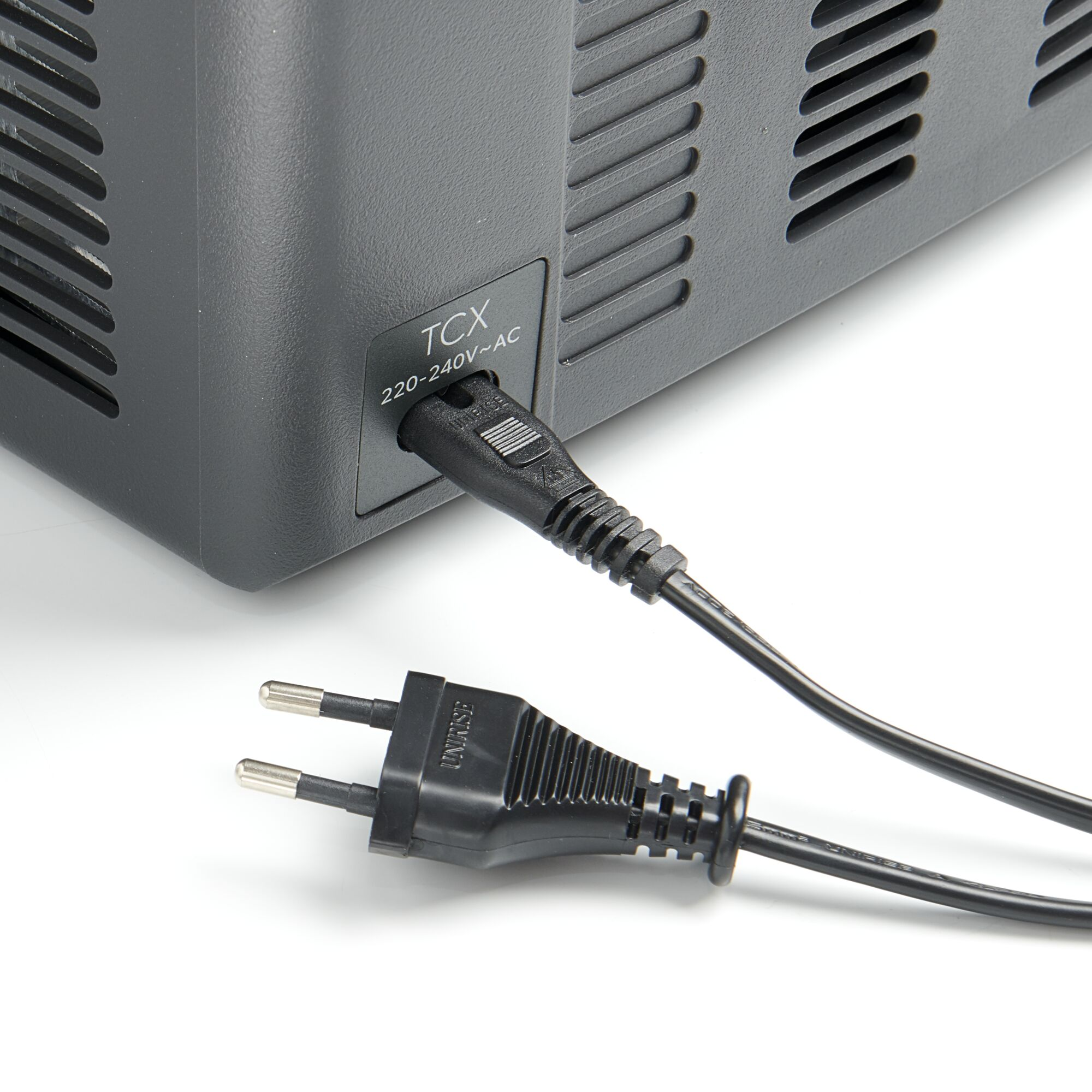 Czarny kabel zasilający podłączony do ciemnoszarego urządzenia z otworami wentylacyjnymi.