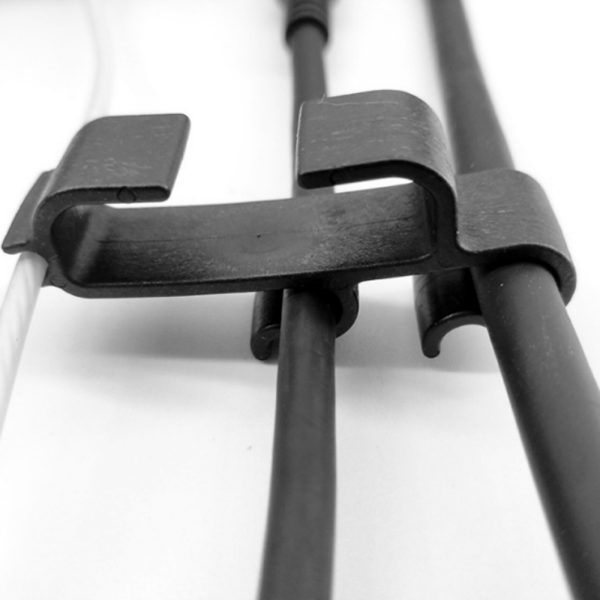 Schwarzer Metallkabelclip, Nahaufnahme, hält mehrere Kabel zusammen.