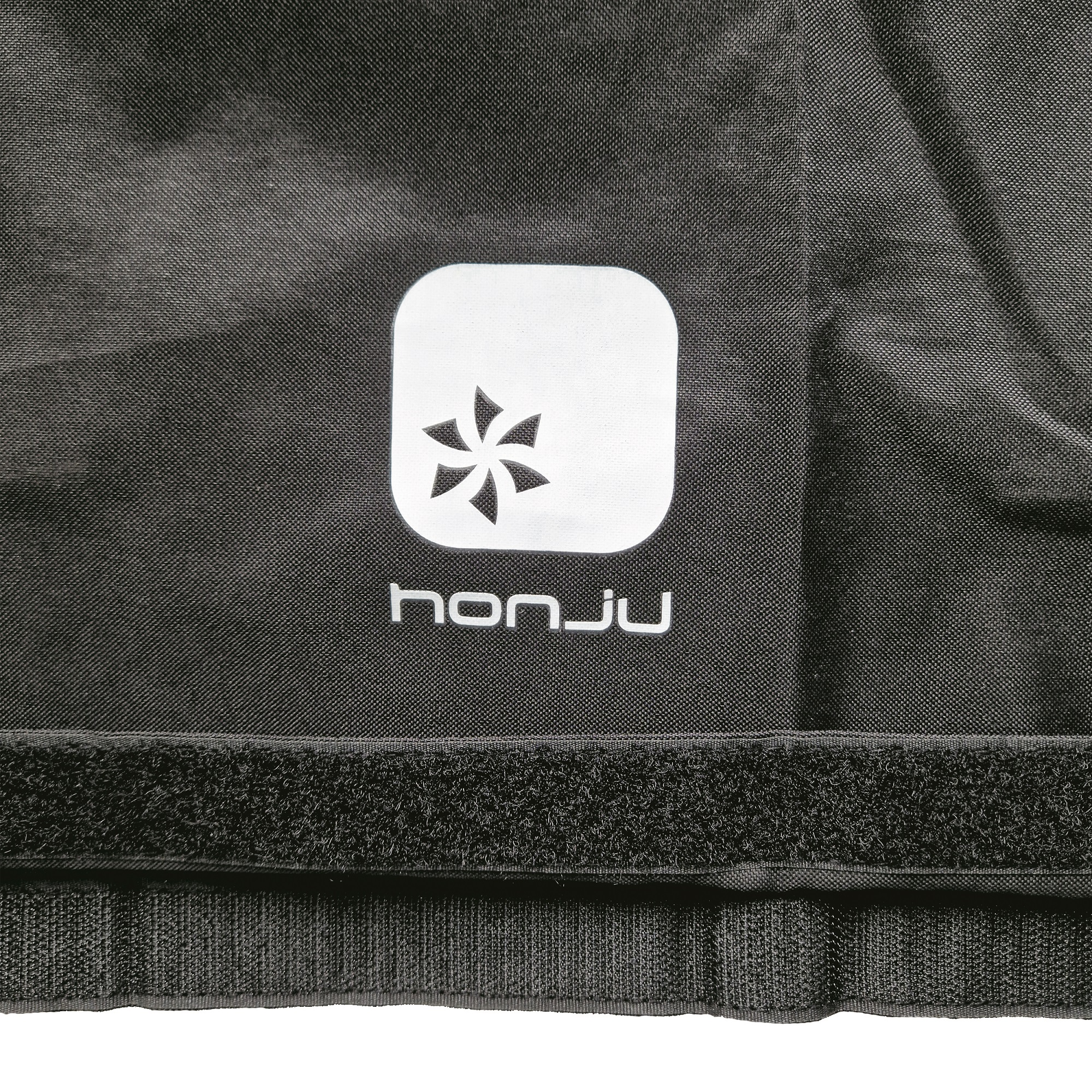 Schwarzer Stoff mit weißem Logo und Klettverschluss.