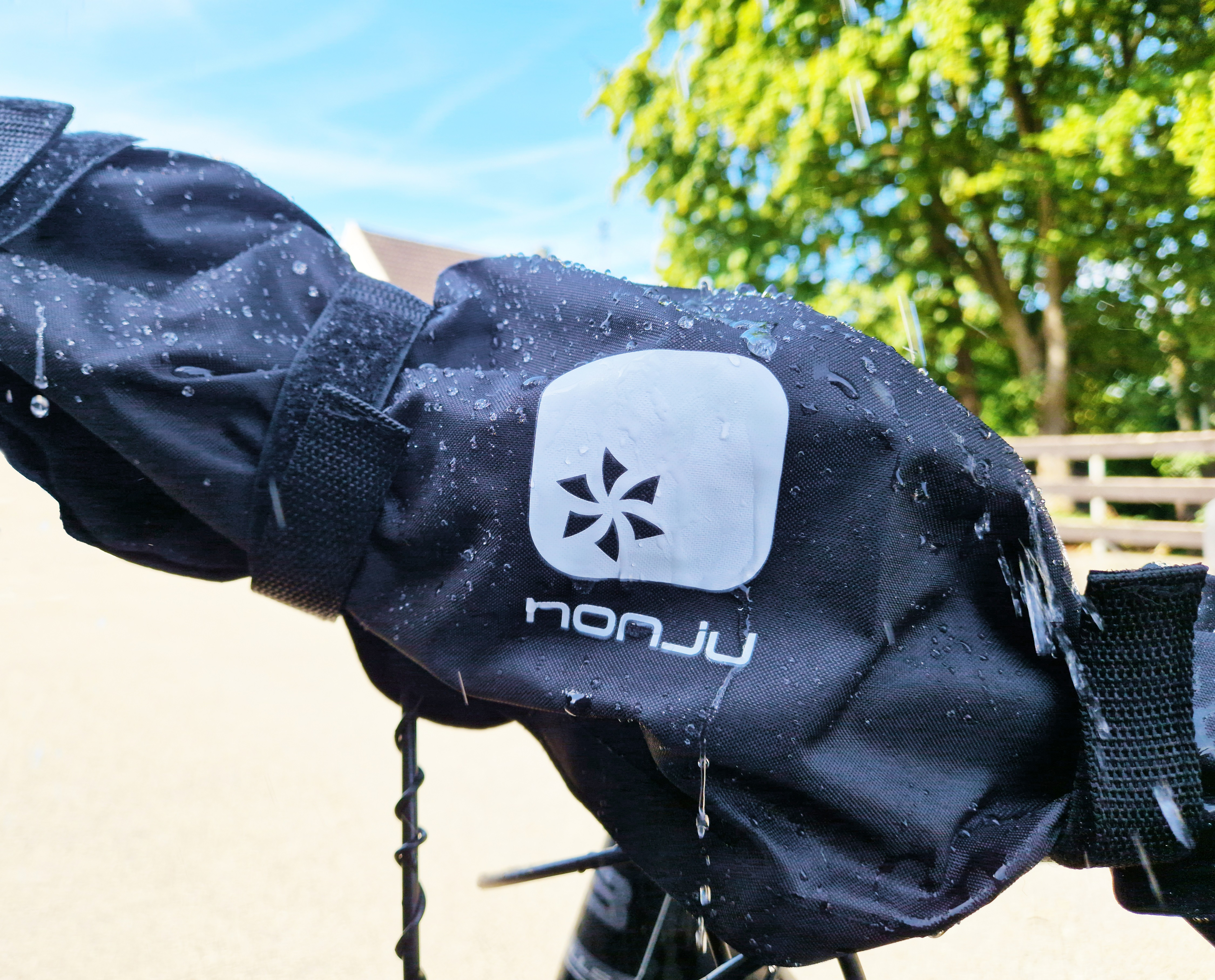 Eine schwarze Stofftasche mit Logo, nass von Wassertropfen.