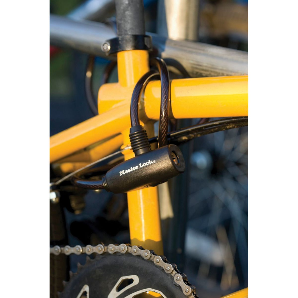 Ein Master Lock Kabelfahrradschloss, das an einem gelben Fahrradrahmen befestigt ist.