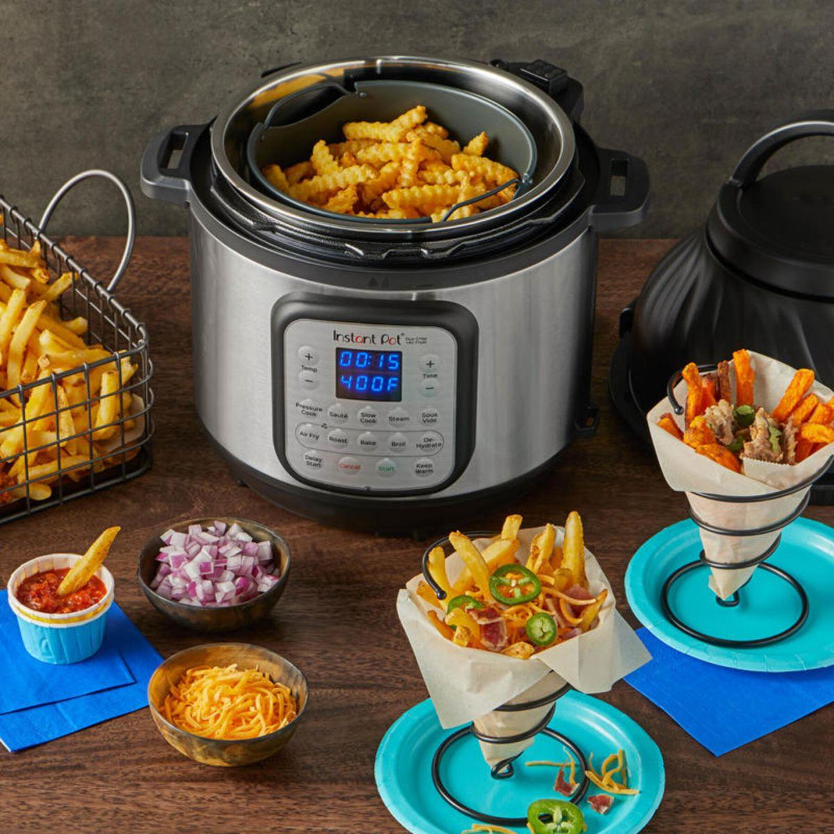 Una Instant Pot con patatine fritte, ciotole di condimenti e patatine fritte in coni di carta.