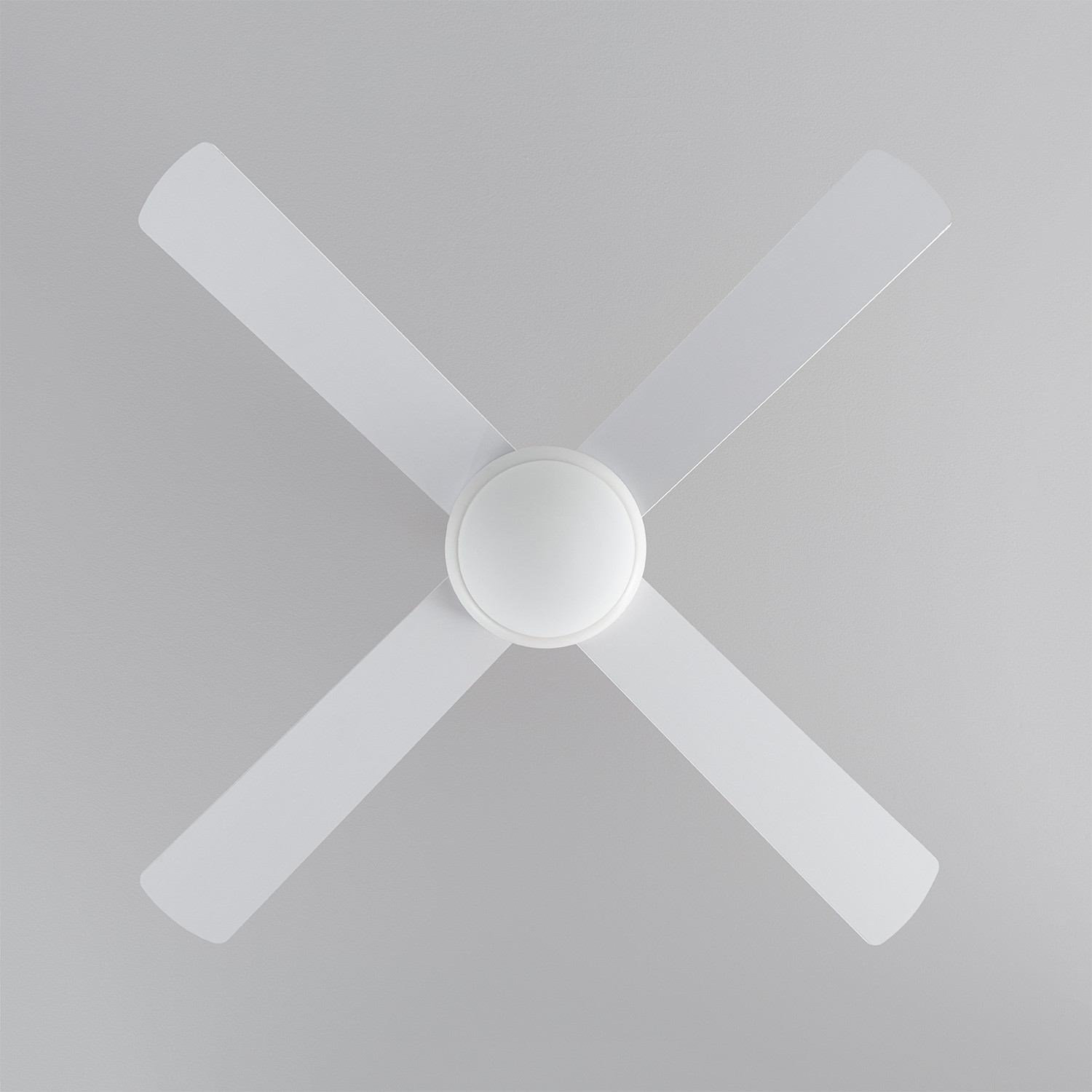 Ventilatore da soffitto con quattro pale bianche e un alloggiamento motore bianco. È montato su un soffitto grigio.