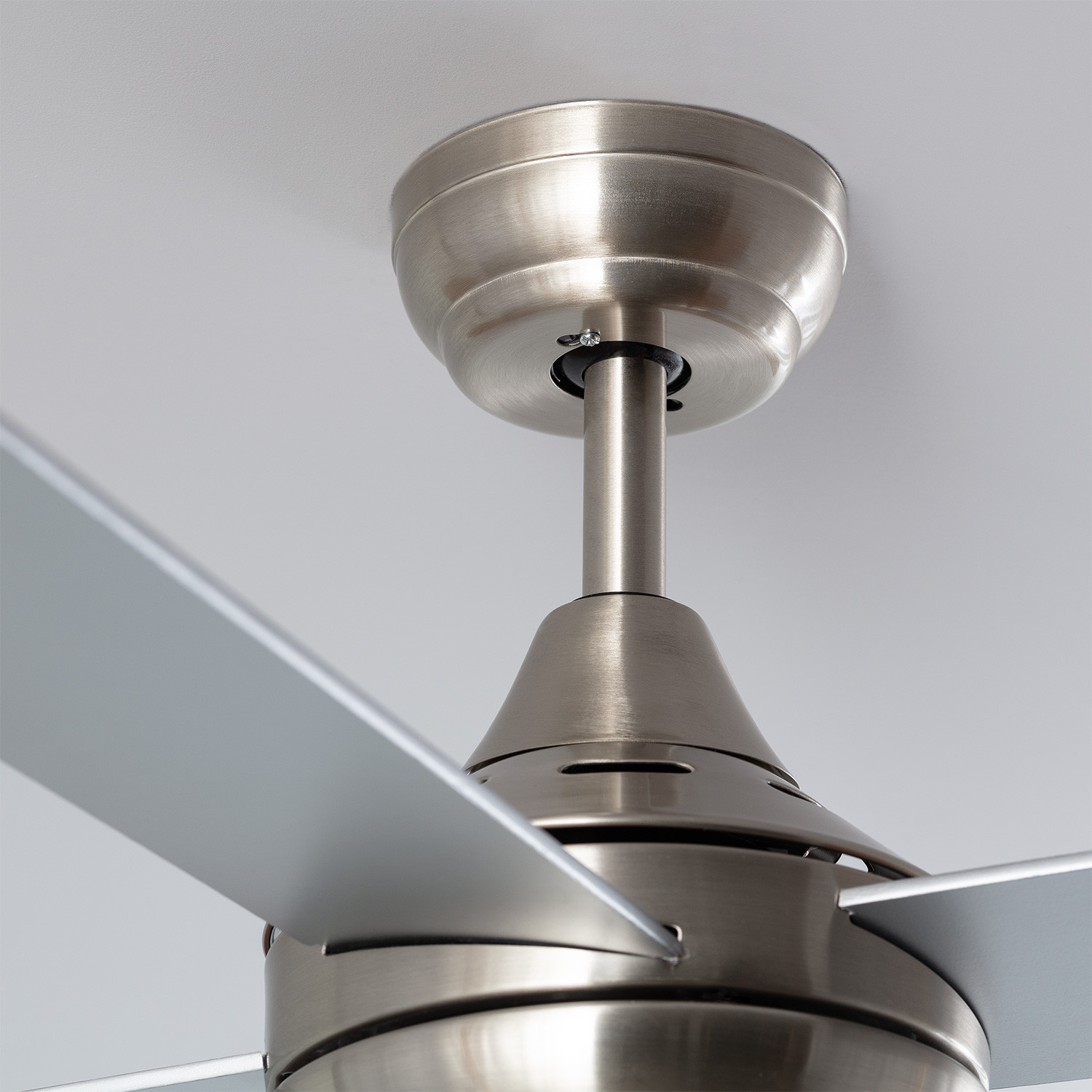 Un ventilatore da soffitto con pale argentate e alloggiamento motore argentato.