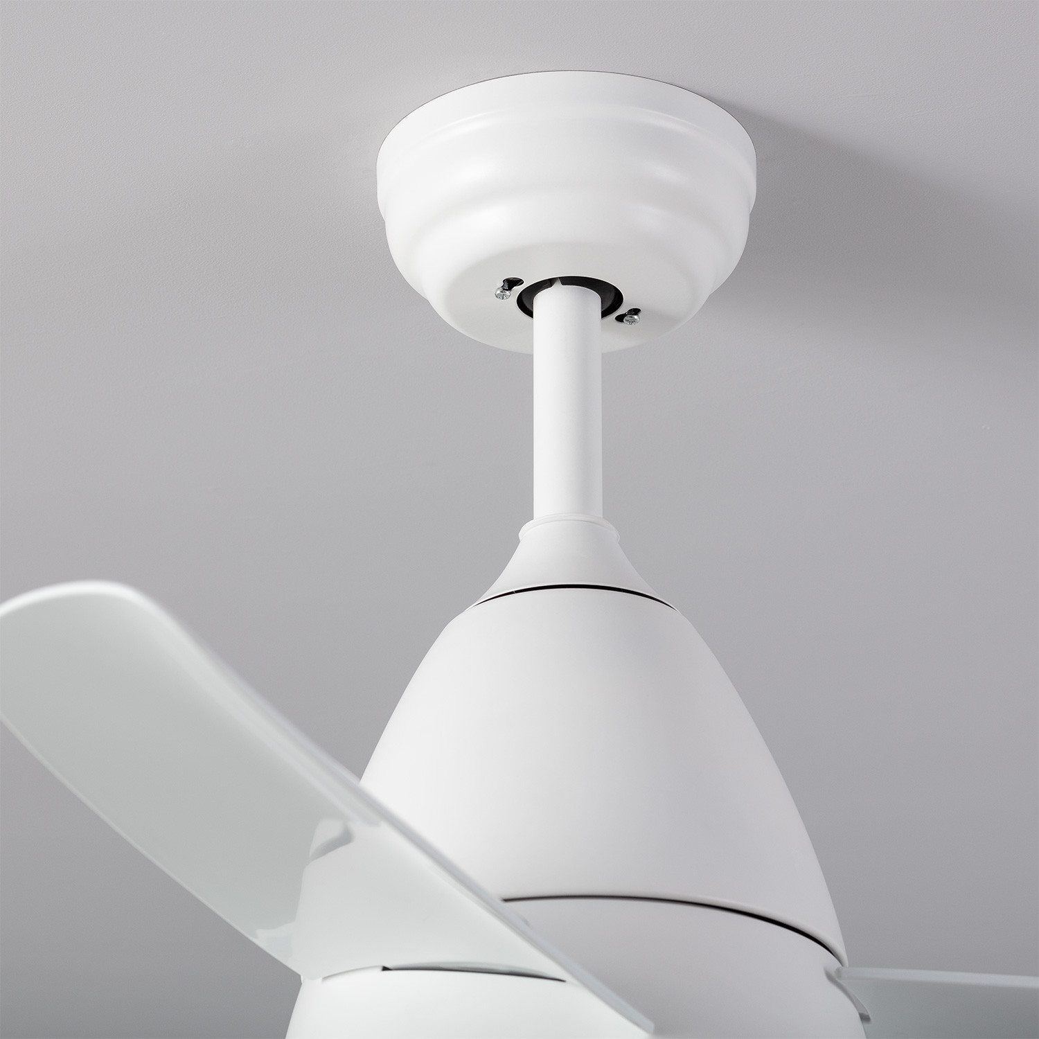 Ventilatore da soffitto bianco. Pale, motore e base visibili, su un soffitto grigio chiaro.