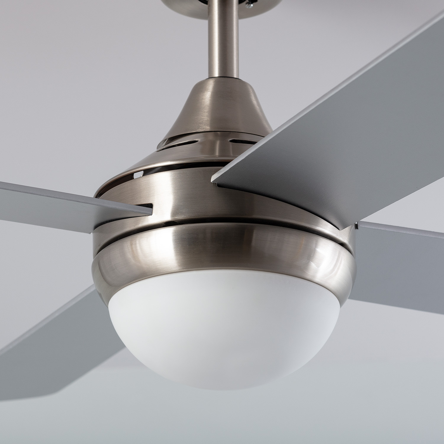 Primo piano di un ventilatore da soffitto, motore e pale argentate.
