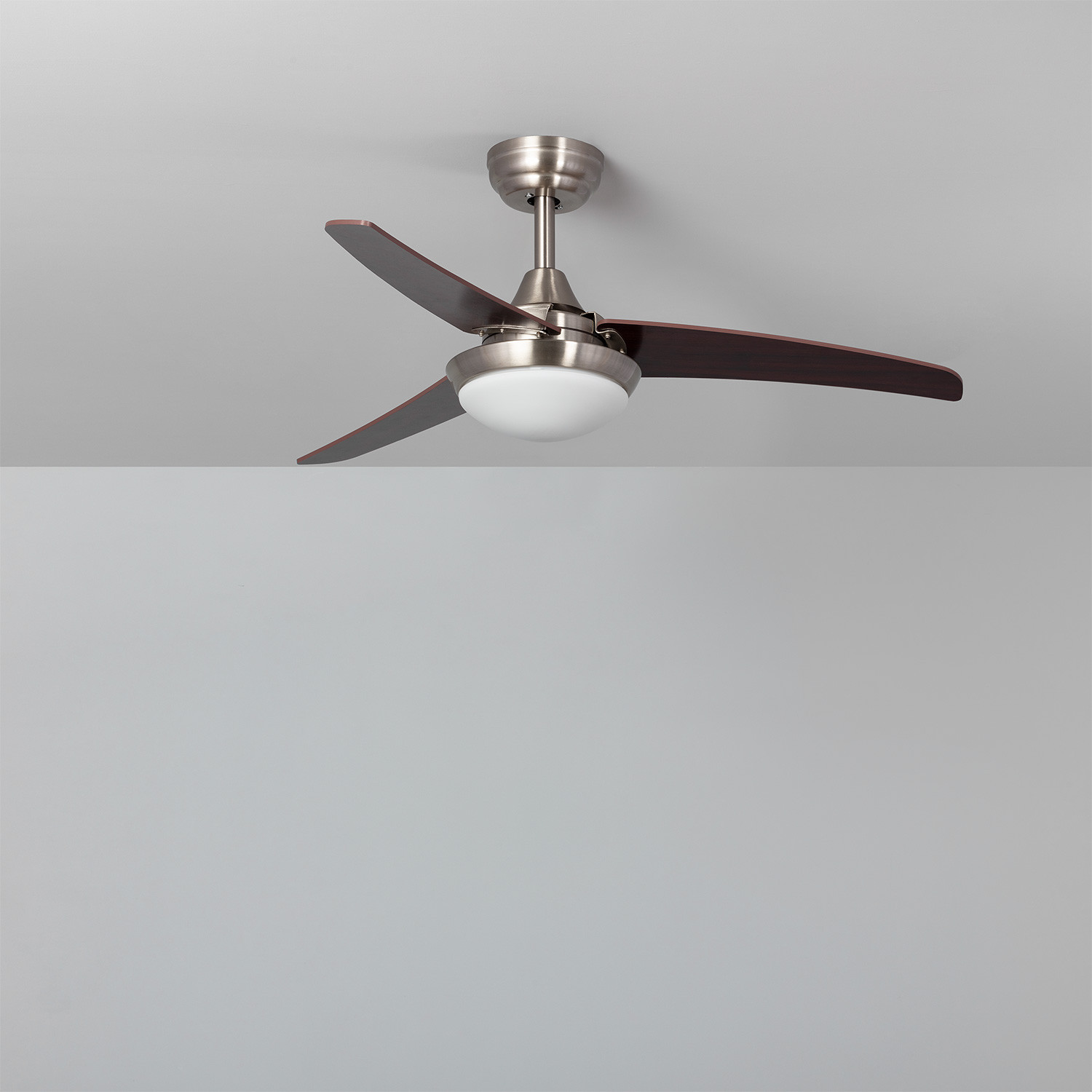 Ventilatore a soffitto con tre pale marrone scuro e un'apparecchio di illuminazione bianco.
