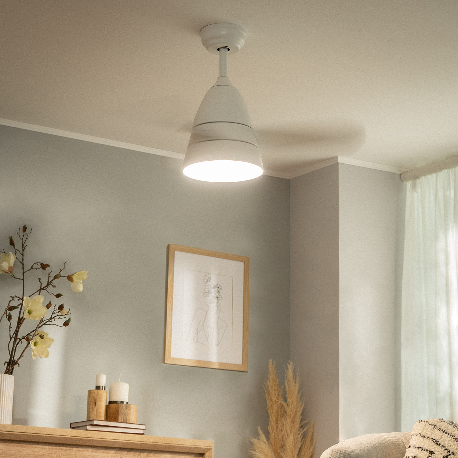 Ventilatore da soffitto bianco con luce, un quadro incorniciato e una cassettiera in una stanza con pareti grigie.