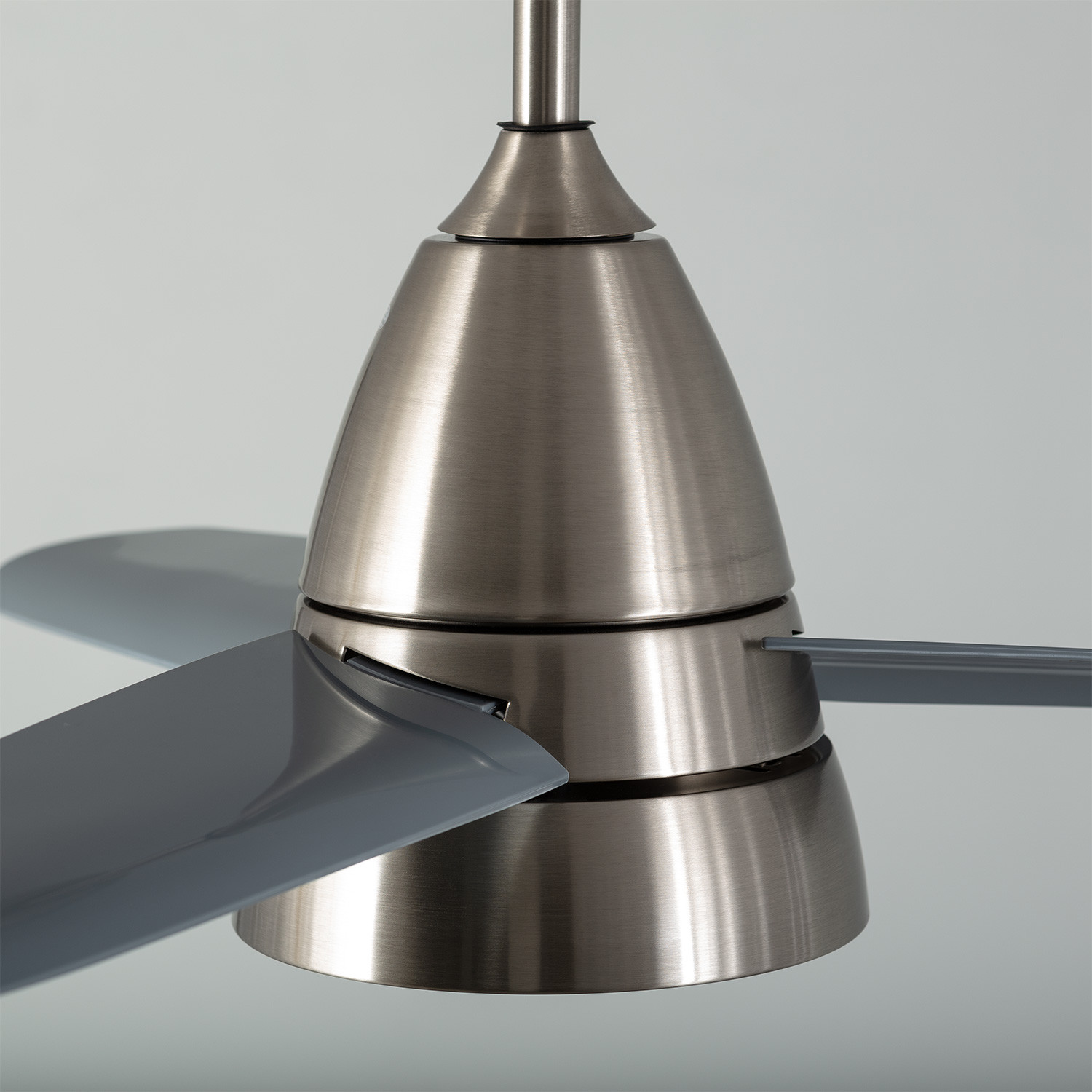 Primo piano di un motore di ventilatore da soffitto con pale grigie.