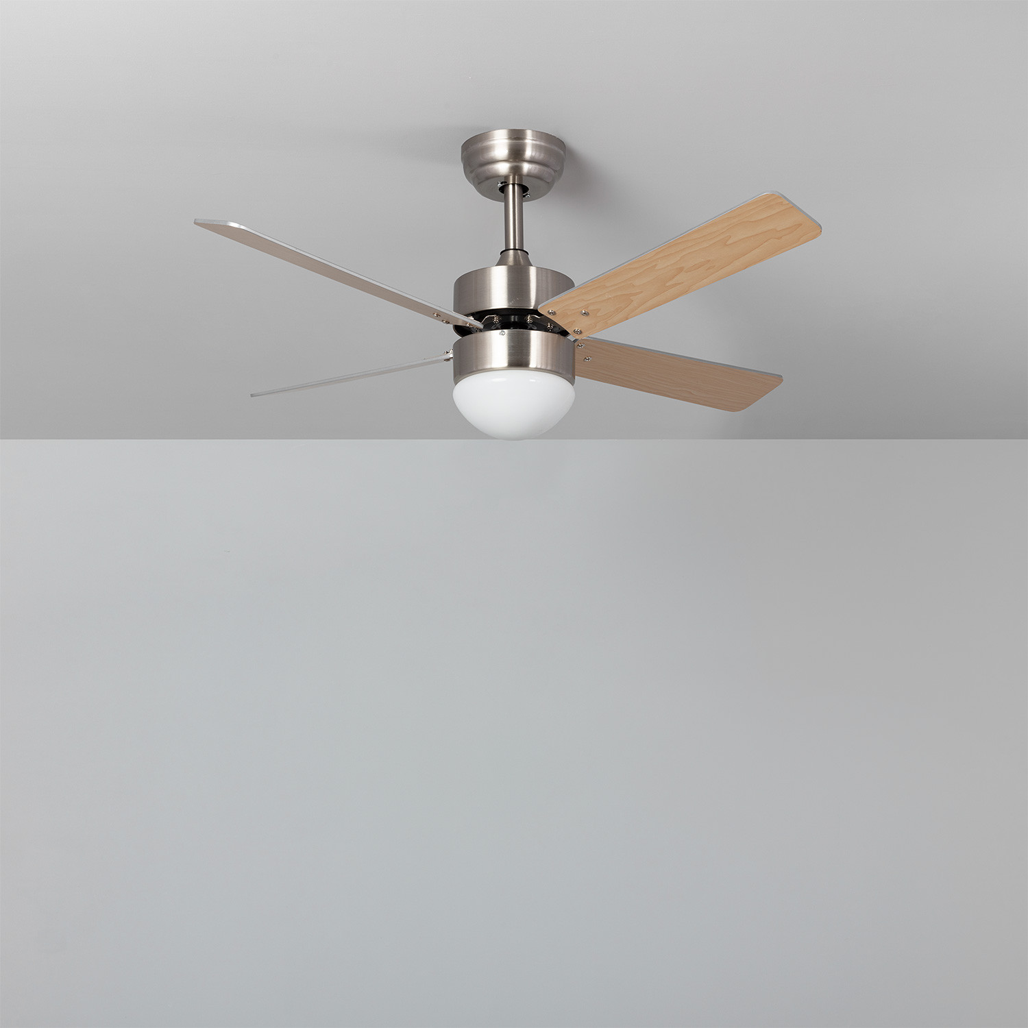Un ventilatore da soffitto con finitura argentata, pale in legno e luce a globo bianca.