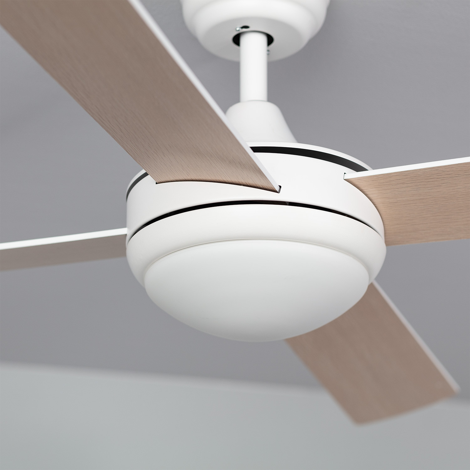 Primo piano di un ventilatore da soffitto bianco con tre pale e una luce. Le pale hanno una finitura in legno.