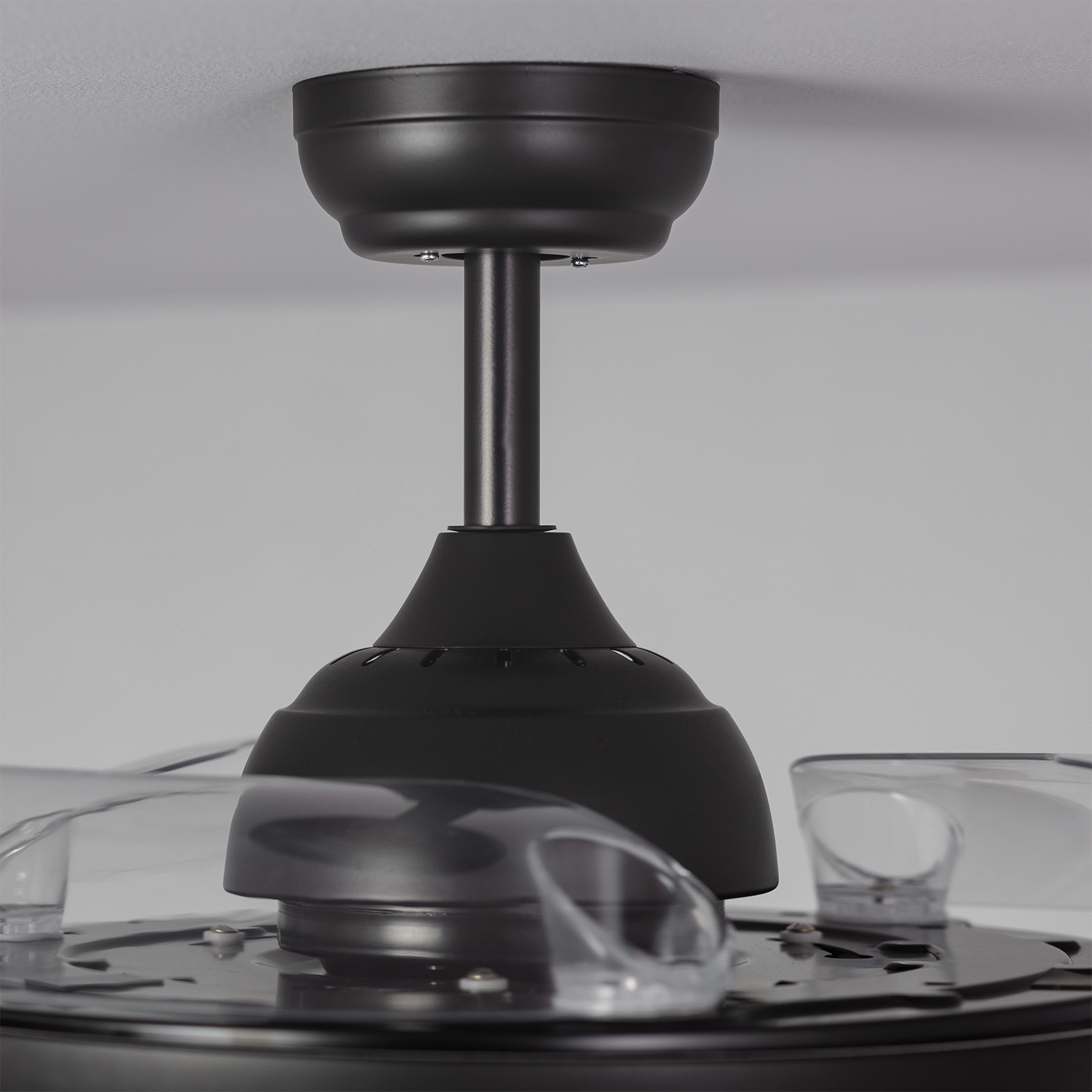 Primo piano di un ventilatore da soffitto nero, con le pale sfocate.
