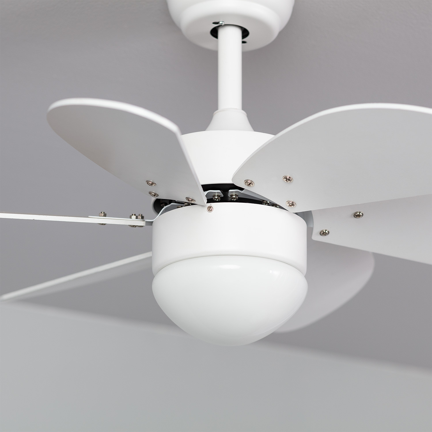 Ventilatore da soffitto bianco con tre pale, luce centrale e soffitto grigio.