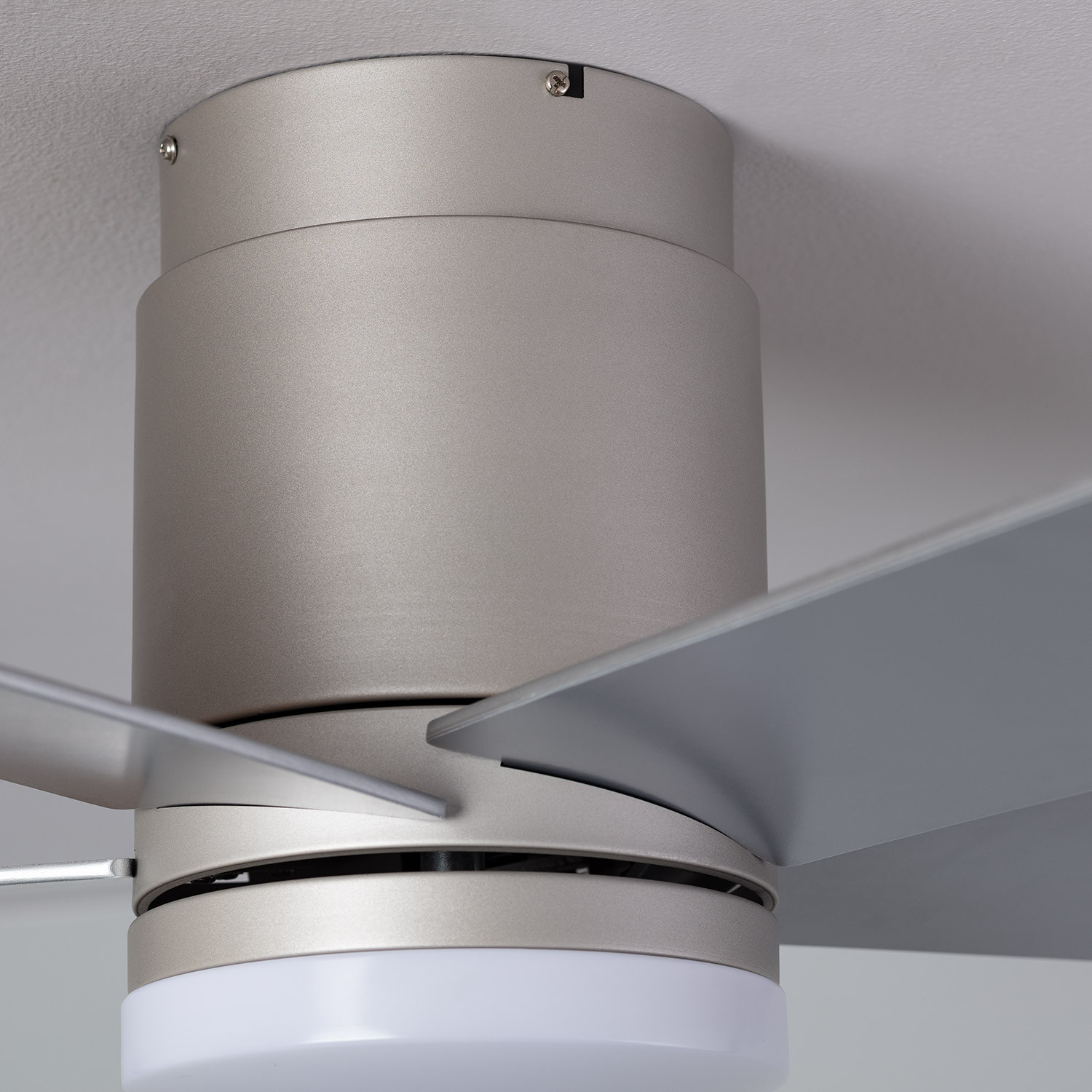 Primo piano di un ventilatore a soffitto argentato dal design moderno, pale visibili.