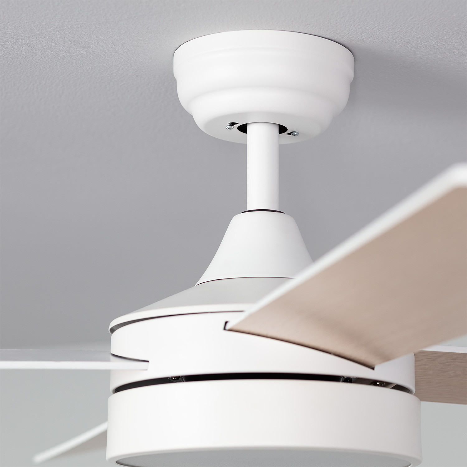 Ventilatore da soffitto, primo piano. Alloggiamento bianco, pale marrone chiaro. Montato su soffitto bianco. Design moderno.