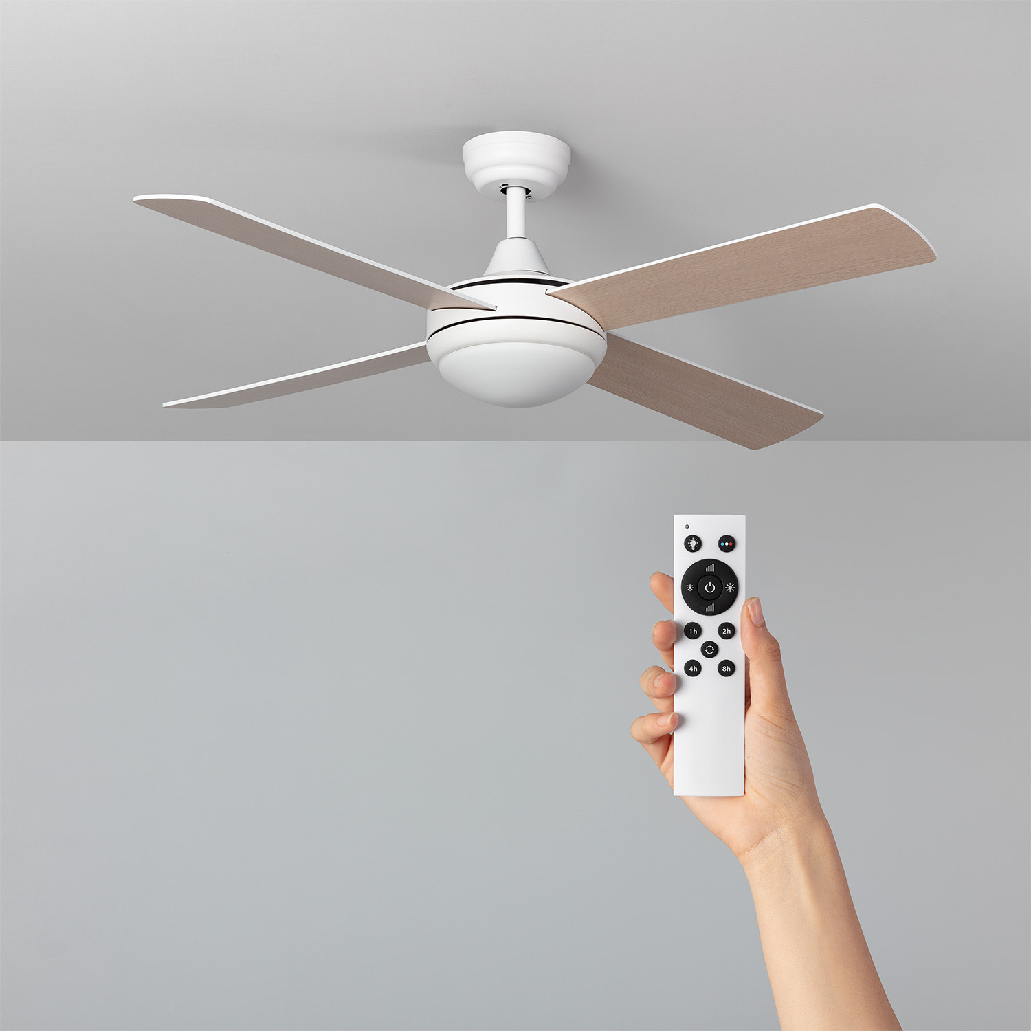 Un ventilatore da soffitto con 4 pale e una mano che tiene un telecomando.