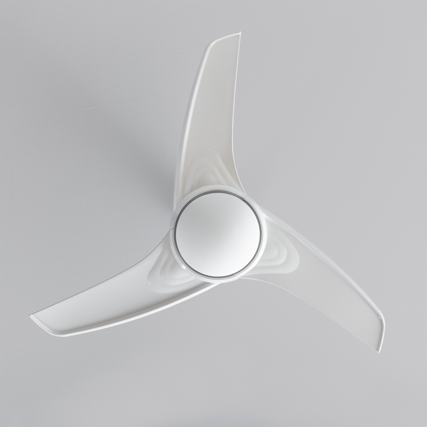 Ventilatore da soffitto bianco con tre pale, alloggiamento centrale. Lo sfondo è bianco.