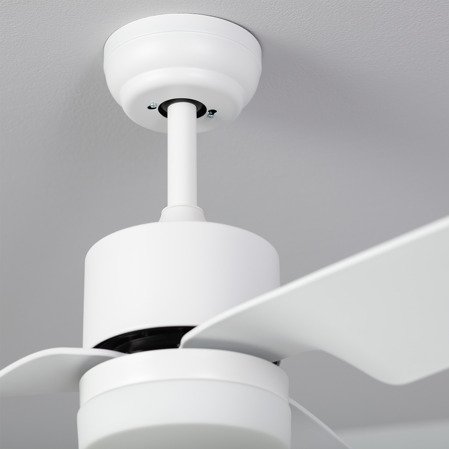 Ventilatore a soffitto bianco, primo piano dell'alloggiamento del motore e delle pale, su un soffitto bianco.