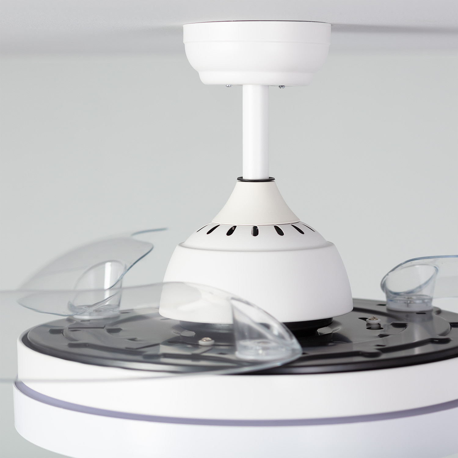Ventilatore a soffitto bianco con pale trasparenti. L'alloggiamento del motore e la base sono bianchi.