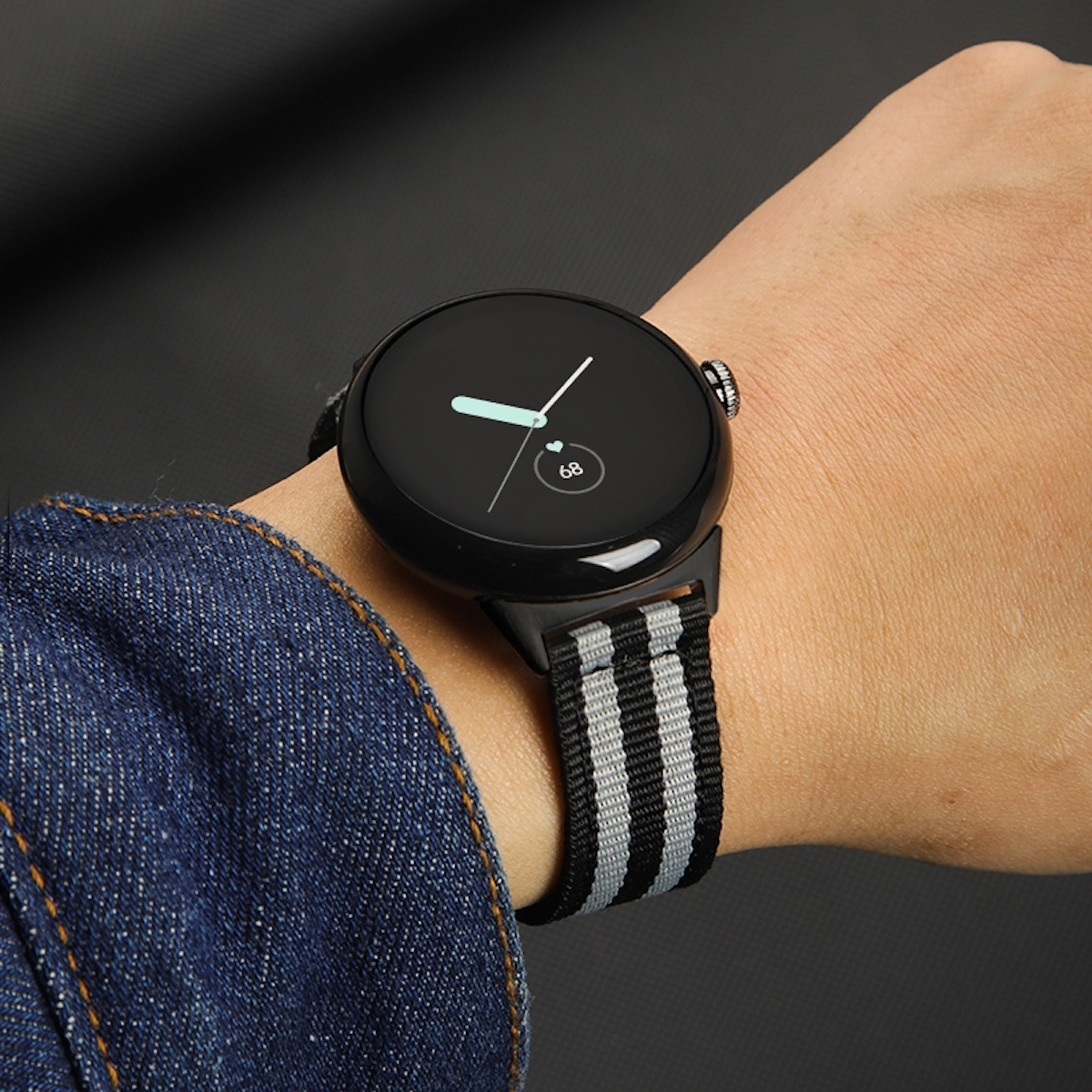 Das Handgelenk einer Person mit einer schwarzen Smartwatch, die Zeit und Herzfrequenz anzeigt.