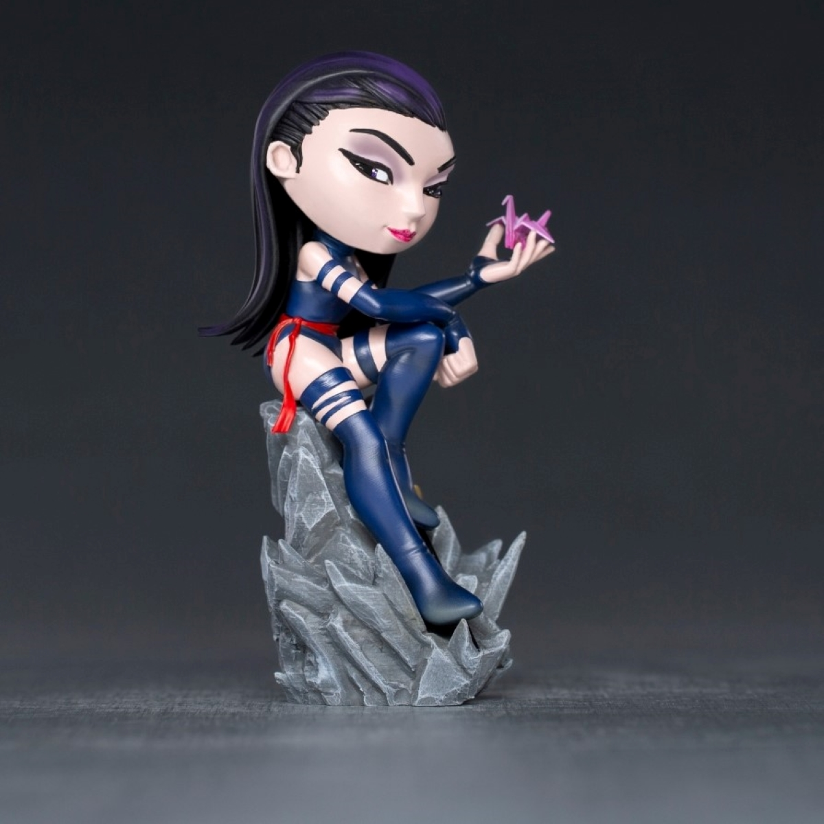 Chibi-Figur eines Comic-Charakters. Die Figur steht auf einem Steinsockel, dunkler Hintergrund.