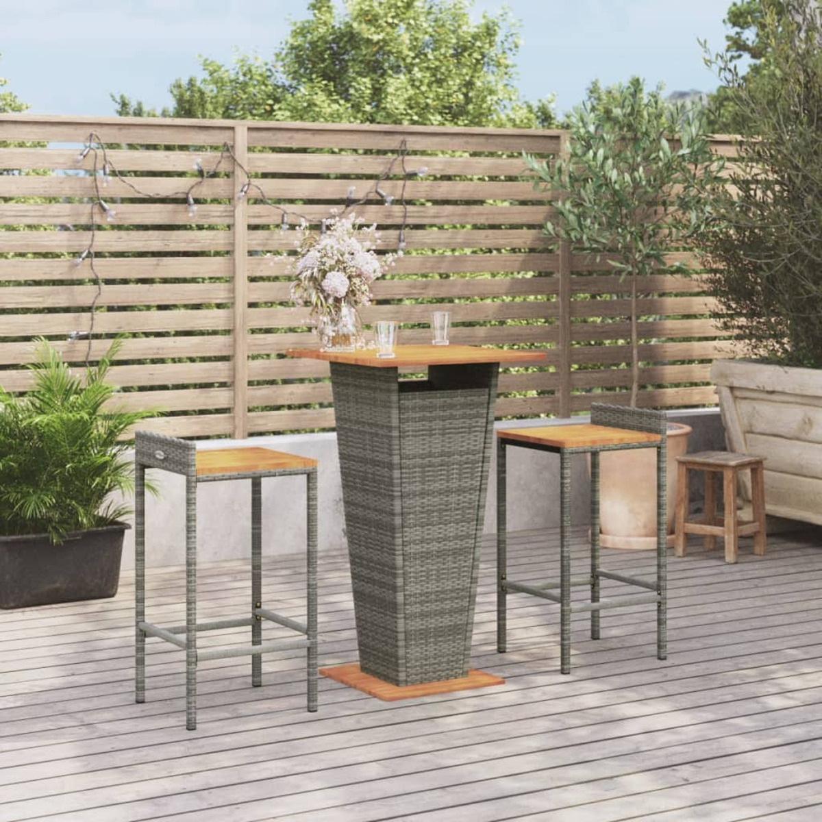 Terrassenset mit grauem Rattantisch und zwei Hockern, im Hintergrund ein Holzzaun.