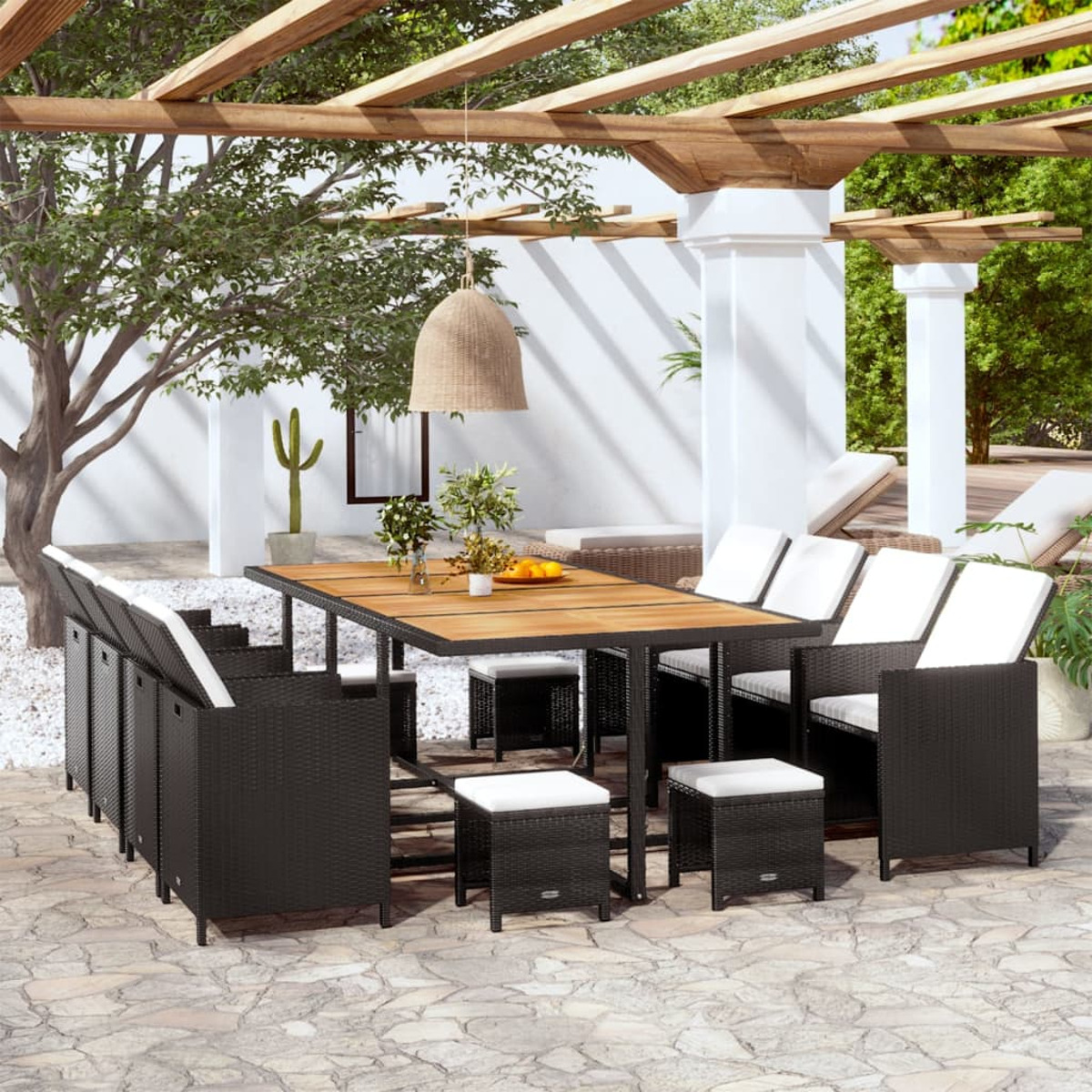 Ein Terrassenset mit schwarzen Korbmöbeln, einem Holztisch und Kissen.