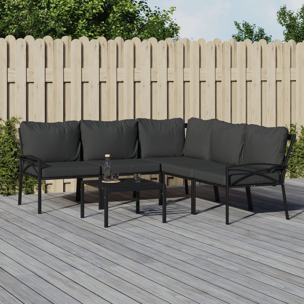 Ein schwarzes Outdoor-Sofa-Set mit einem Tisch und einem Holzzaun.