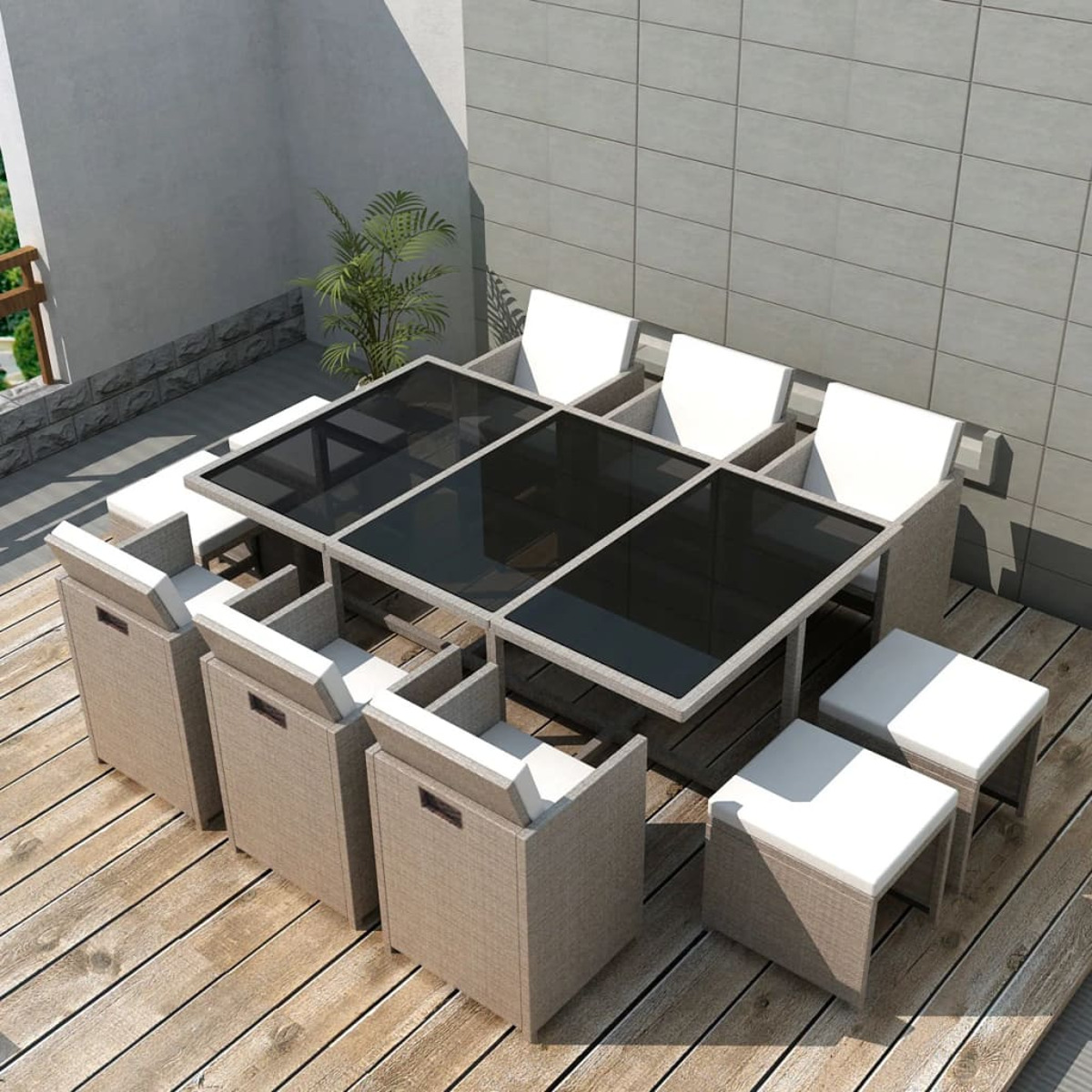 Ein Ess-Set im Freien auf einem Holzdeck mit einem Tisch aus schwarzem Glas, beigen Stühlen und Hockern. Draufsicht.