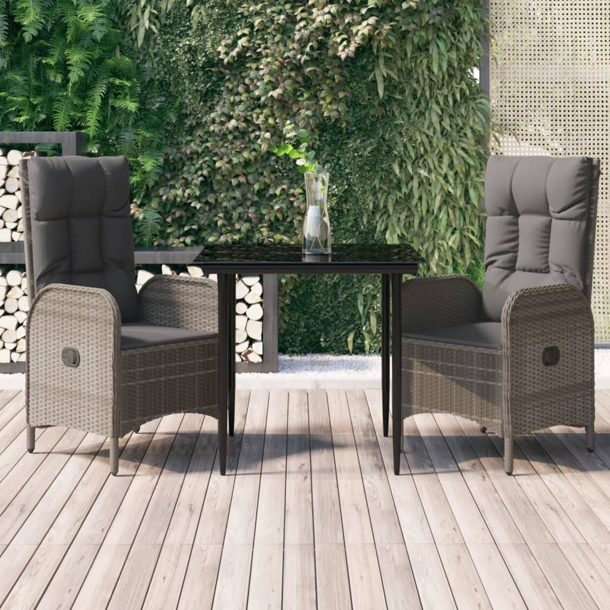 Korbstühle und Tisch, mit Kissen, auf Holzterrasse, grüne Wand im Hintergrund.