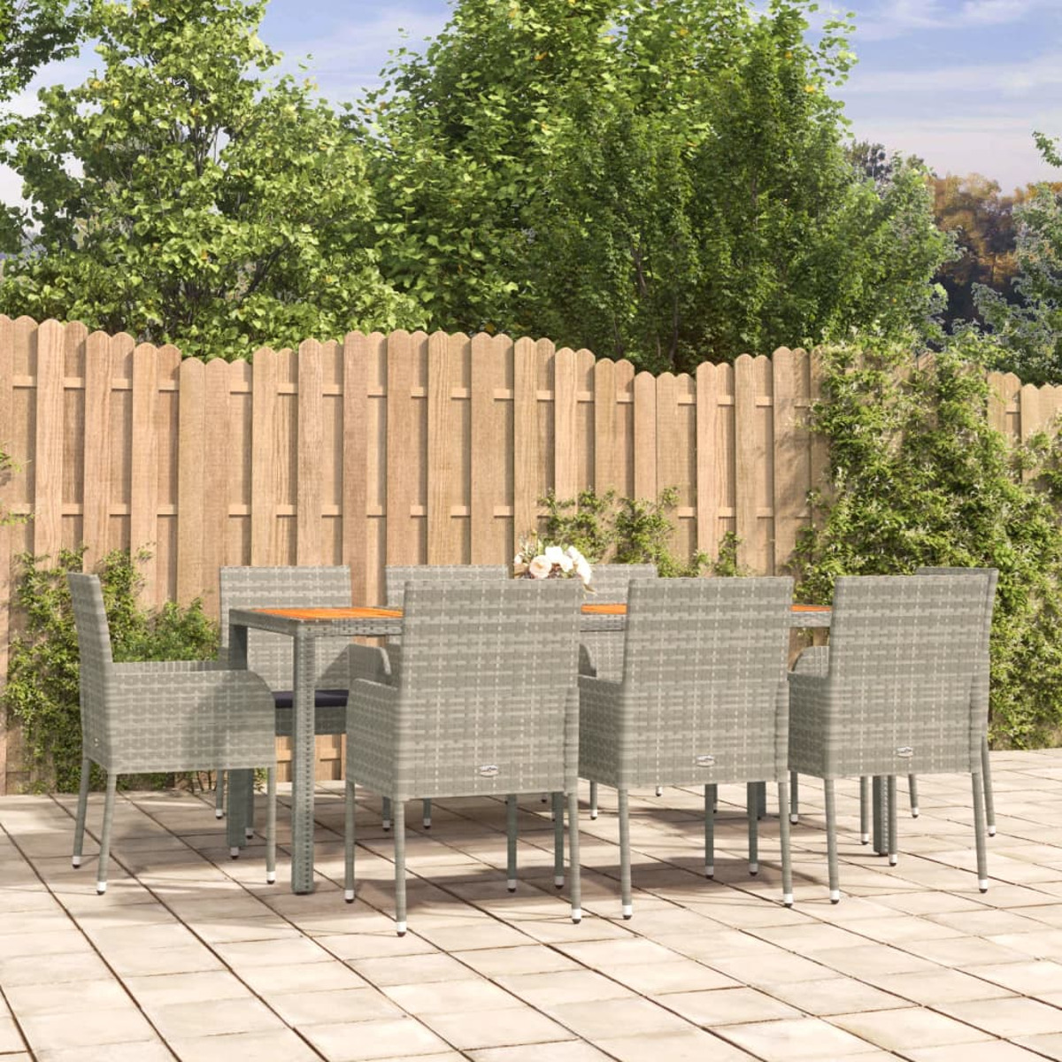 Essgruppe im Freien. Rattan-Stühle umrunden einen Holztisch auf einer Terrasse.