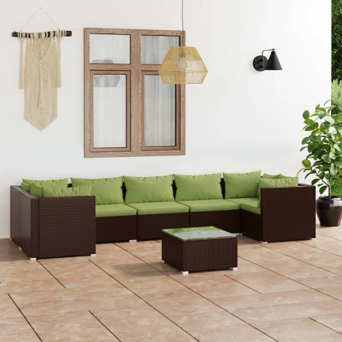 Gartenmöbel-Set mit braunem Korbgeflecht, grünen Kissen und Glastisch. Weiße Wand.