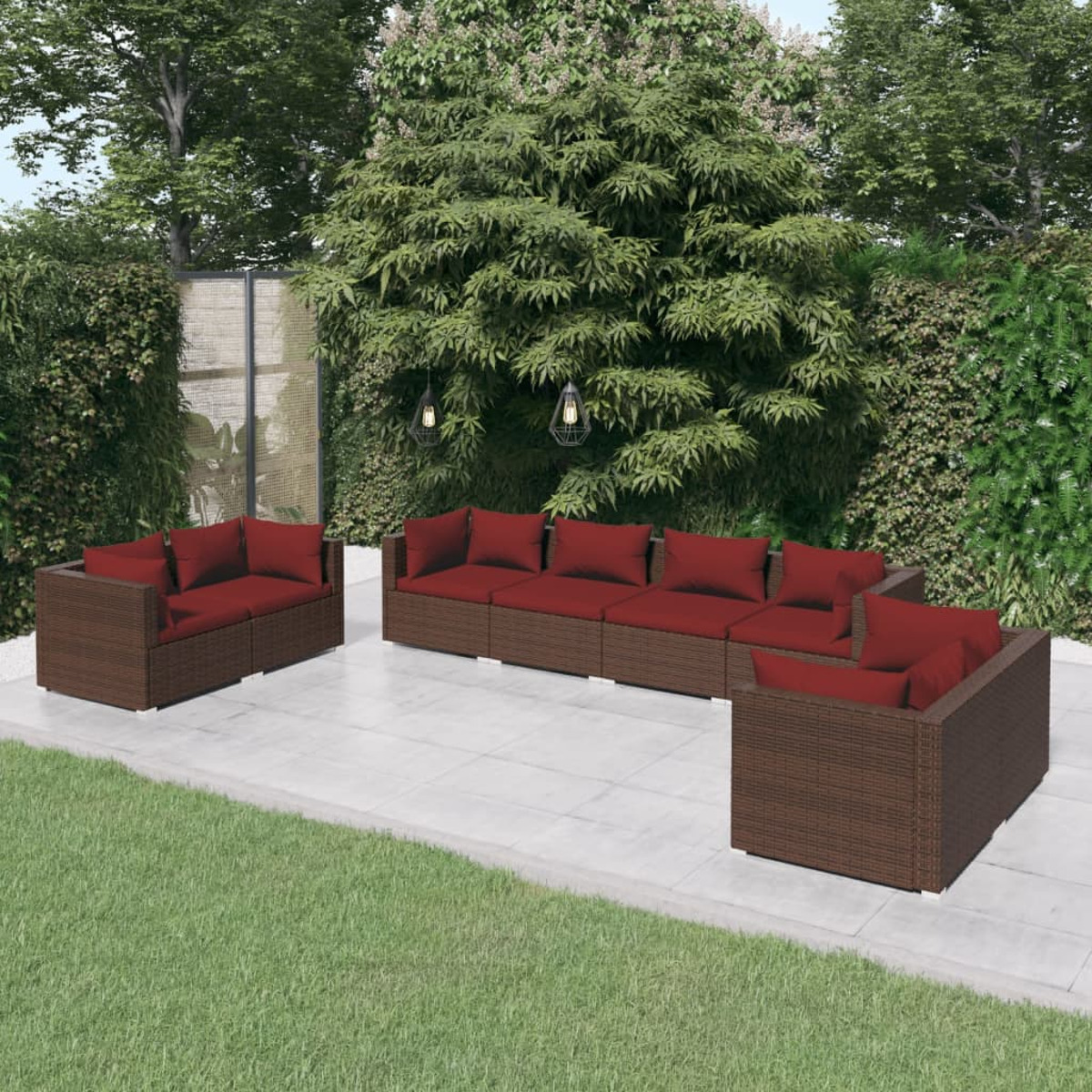 Sitzbereich im Freien mit braunen Rattan-Sofas und roten Kissen. Grüner Hintergrund mit Gras.