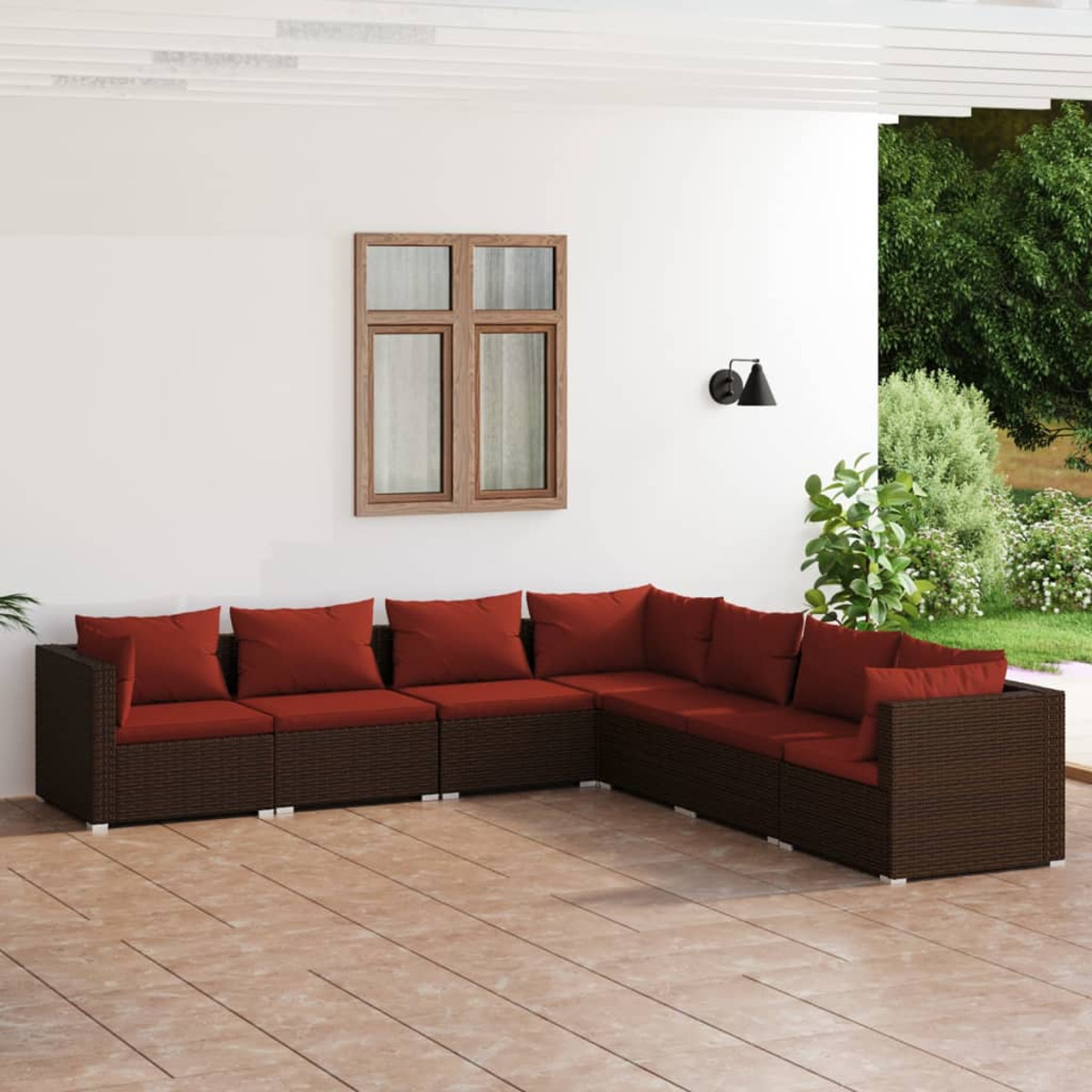 Outdoor-Ecksofa mit braunem Korbgeflecht und roten Kissen. Auf einer Terrasse mit weißer Wand.