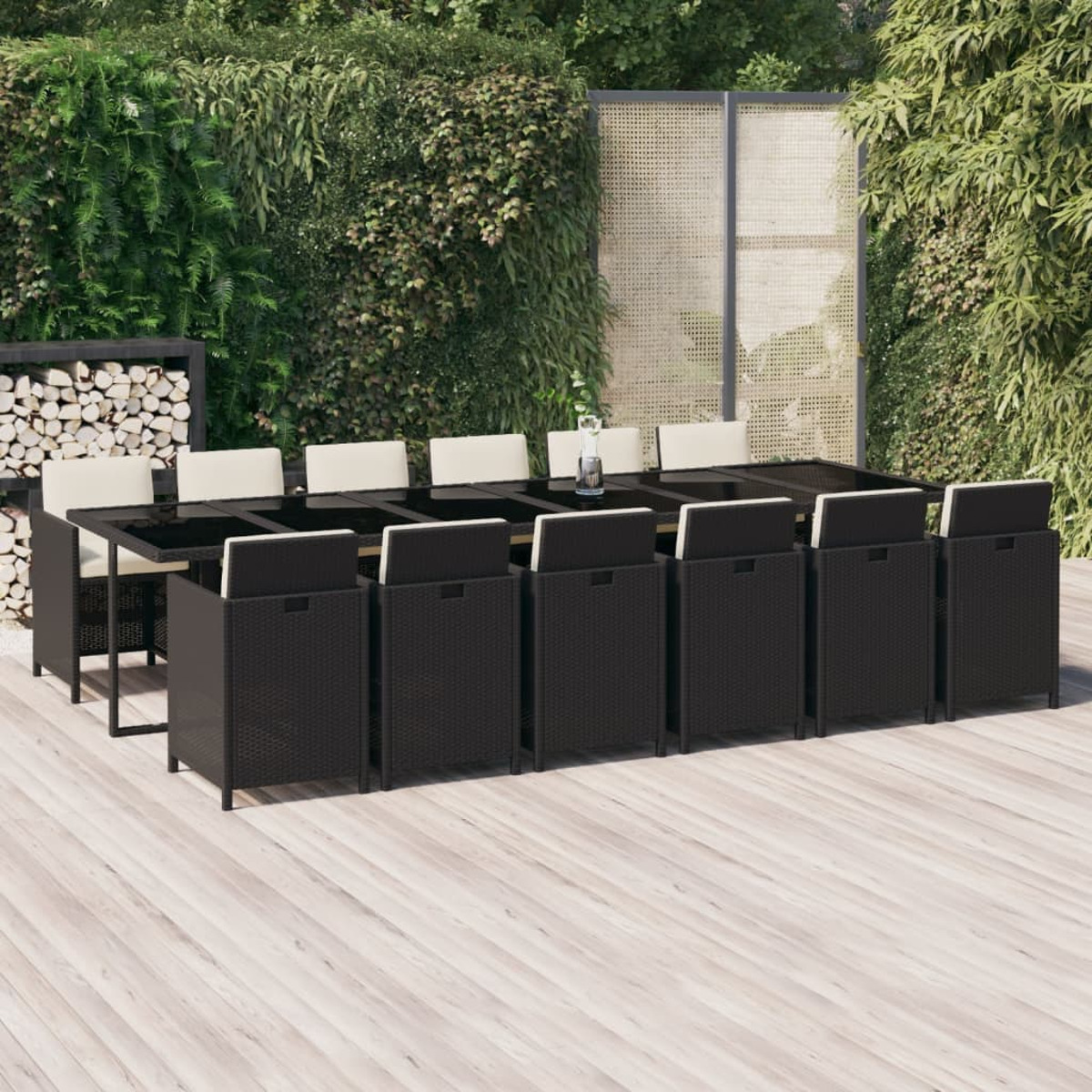 Essgruppe im Freien mit einem schwarzen Tisch und Stühlen. Weiße Kissen. Holzterrasse im Hintergrund.