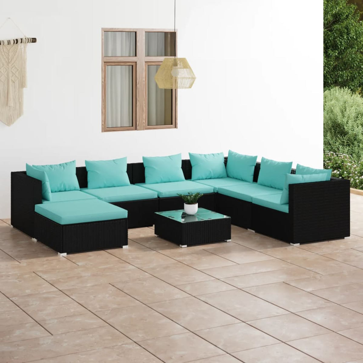 Schwarzes Outdoor-Ecksofa mit türkisfarbenen Kissen auf einer Terrasse. Weiße Wand im Hintergrund. Quadratischer Glastisch.