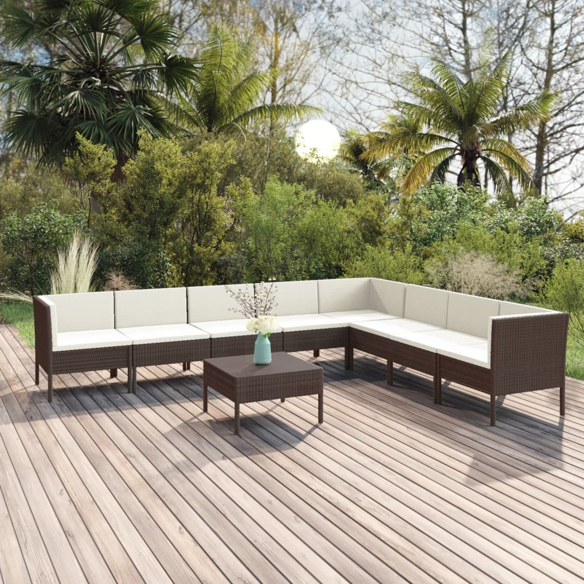 Braunes Korbmöbel mit weißen Kissen und Tisch auf einer Holzterrasse.