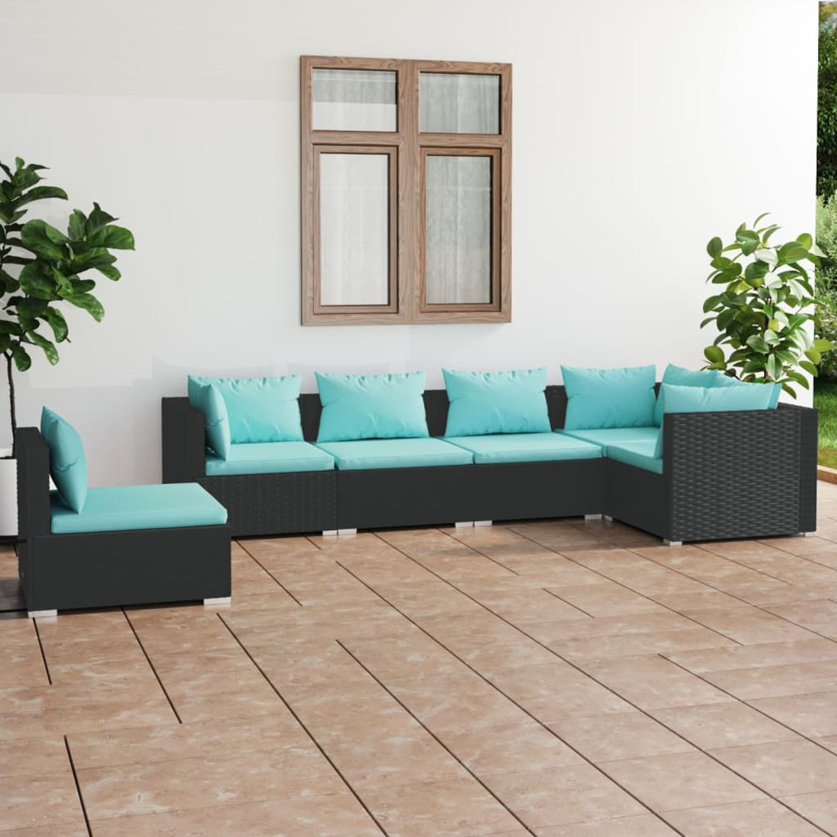 Schwarzer Rattan-Schnitt mit blauen Kissen auf der Terrasse. Weiße Wand und Pflanzen.