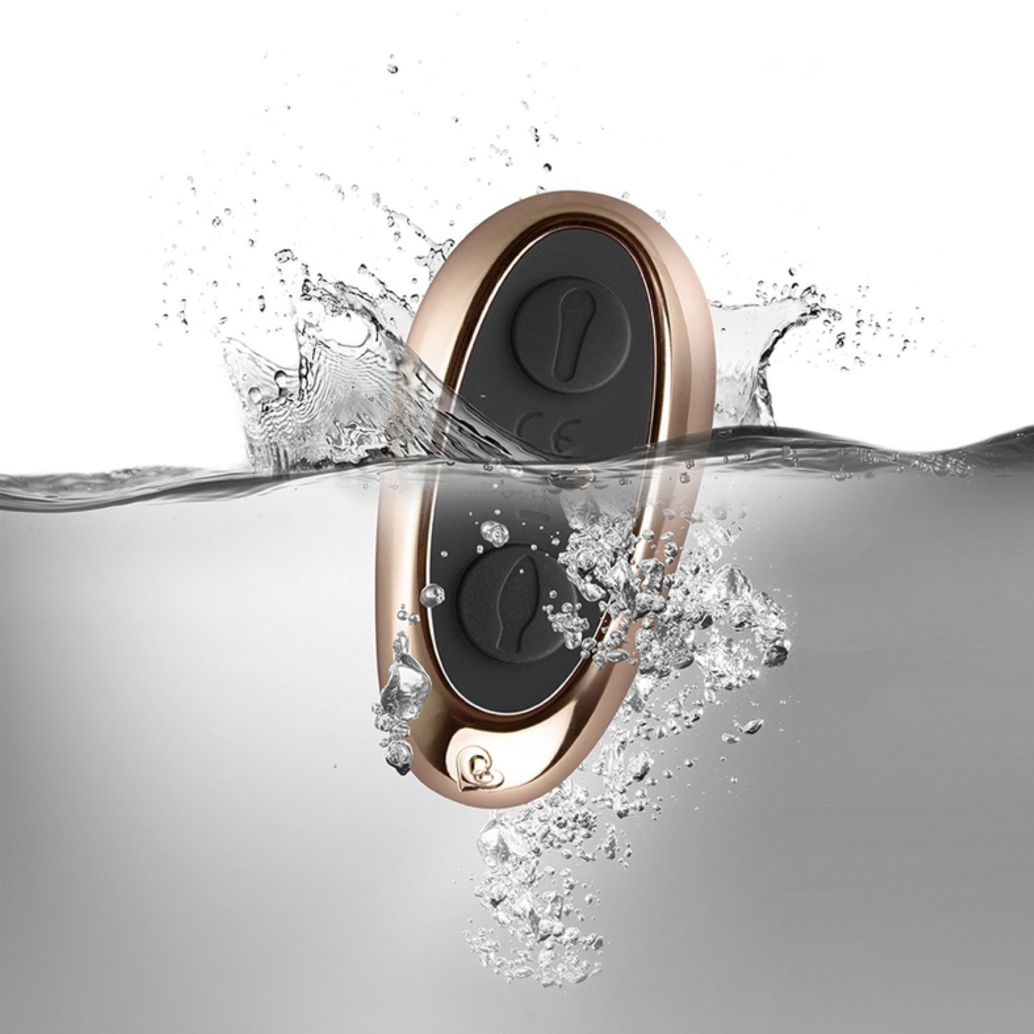 Mando a distancia dorado y negro sumergido en agua con gotas de agua.