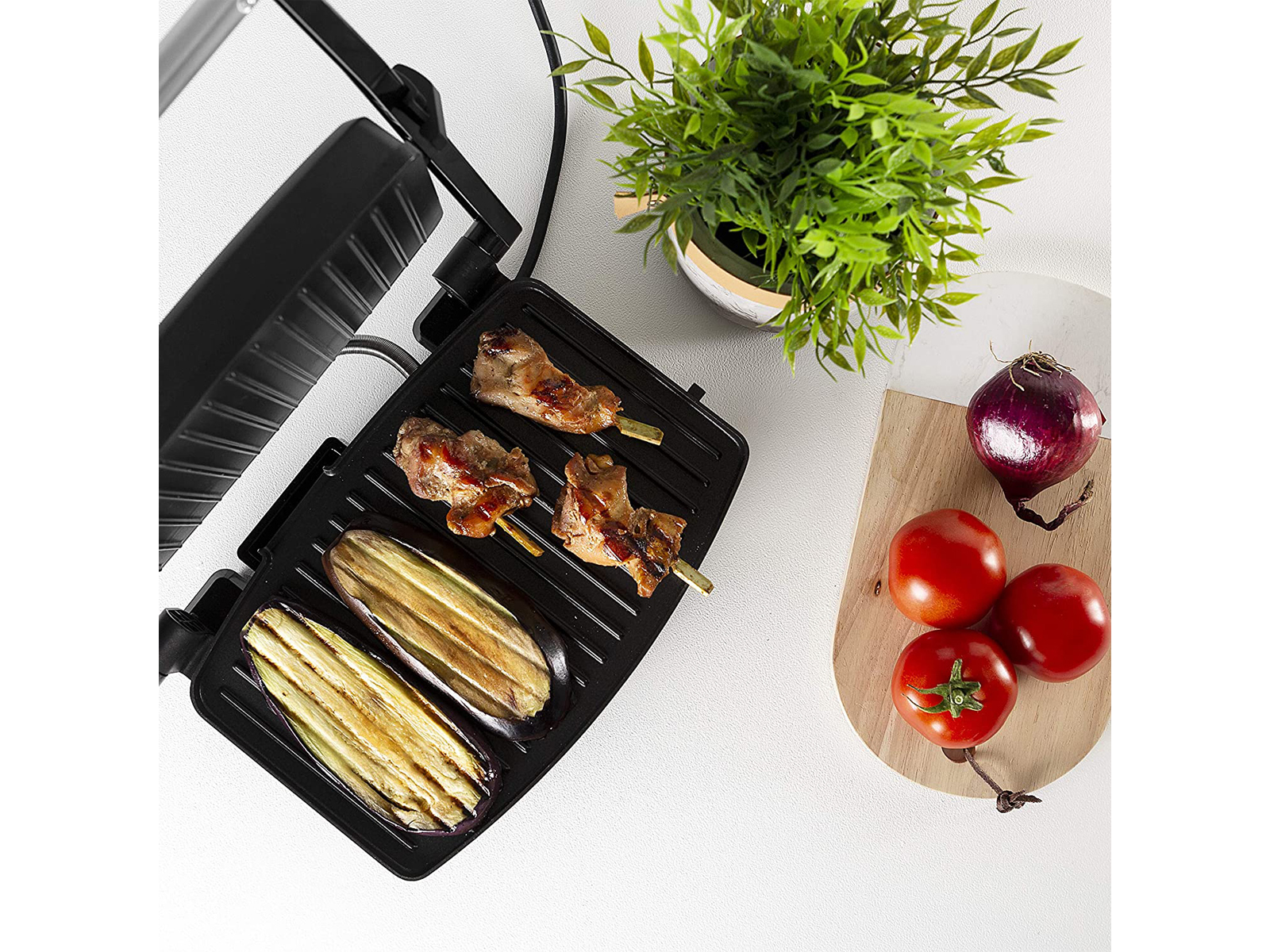 Grill mit Speisen, einschließlich gegrilltem Gemüse und Spießen, mit Tomaten und Zwiebeln.