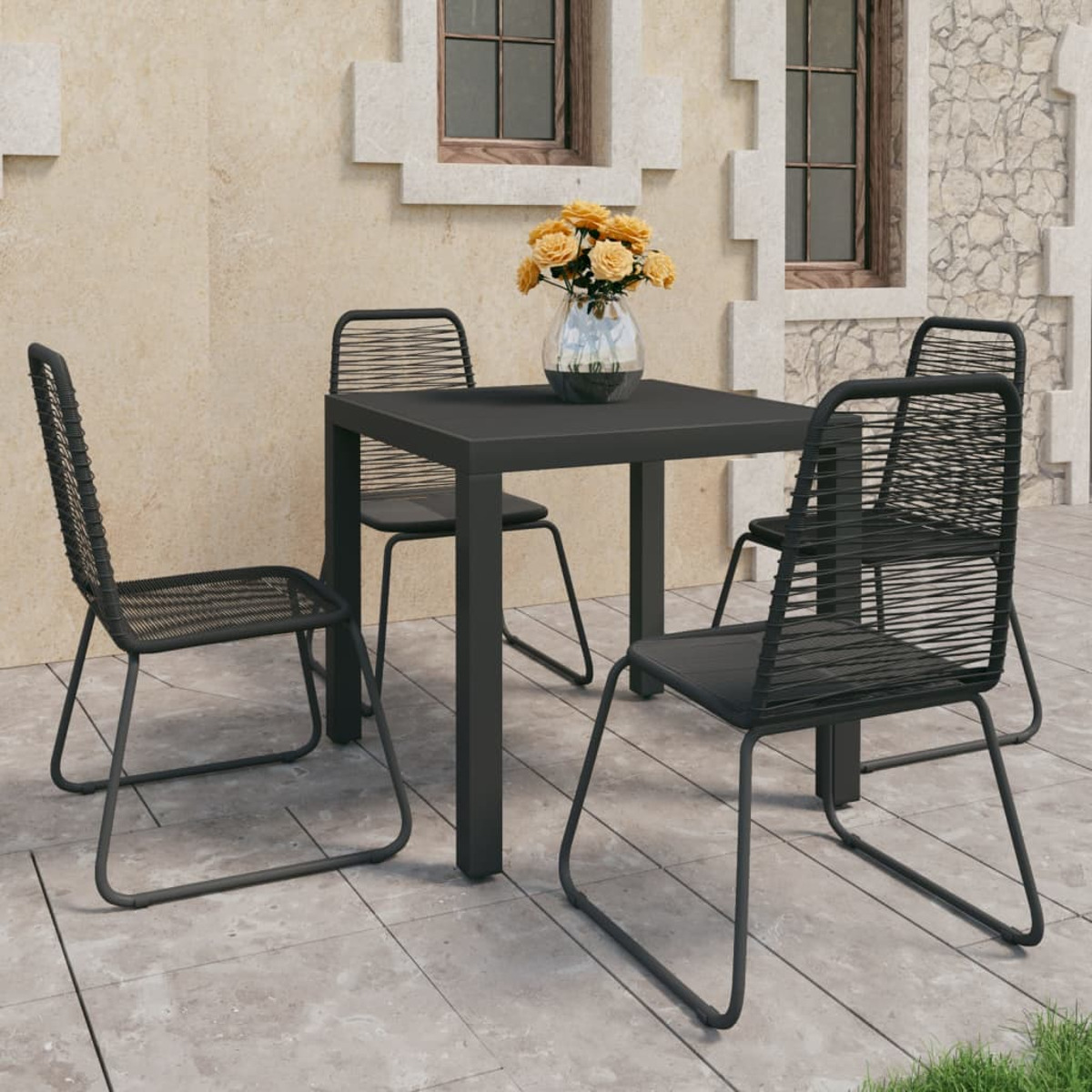 Essgruppe im Freien. Schwarzer Tisch und Stühle. Beiger Wandhintergrund.