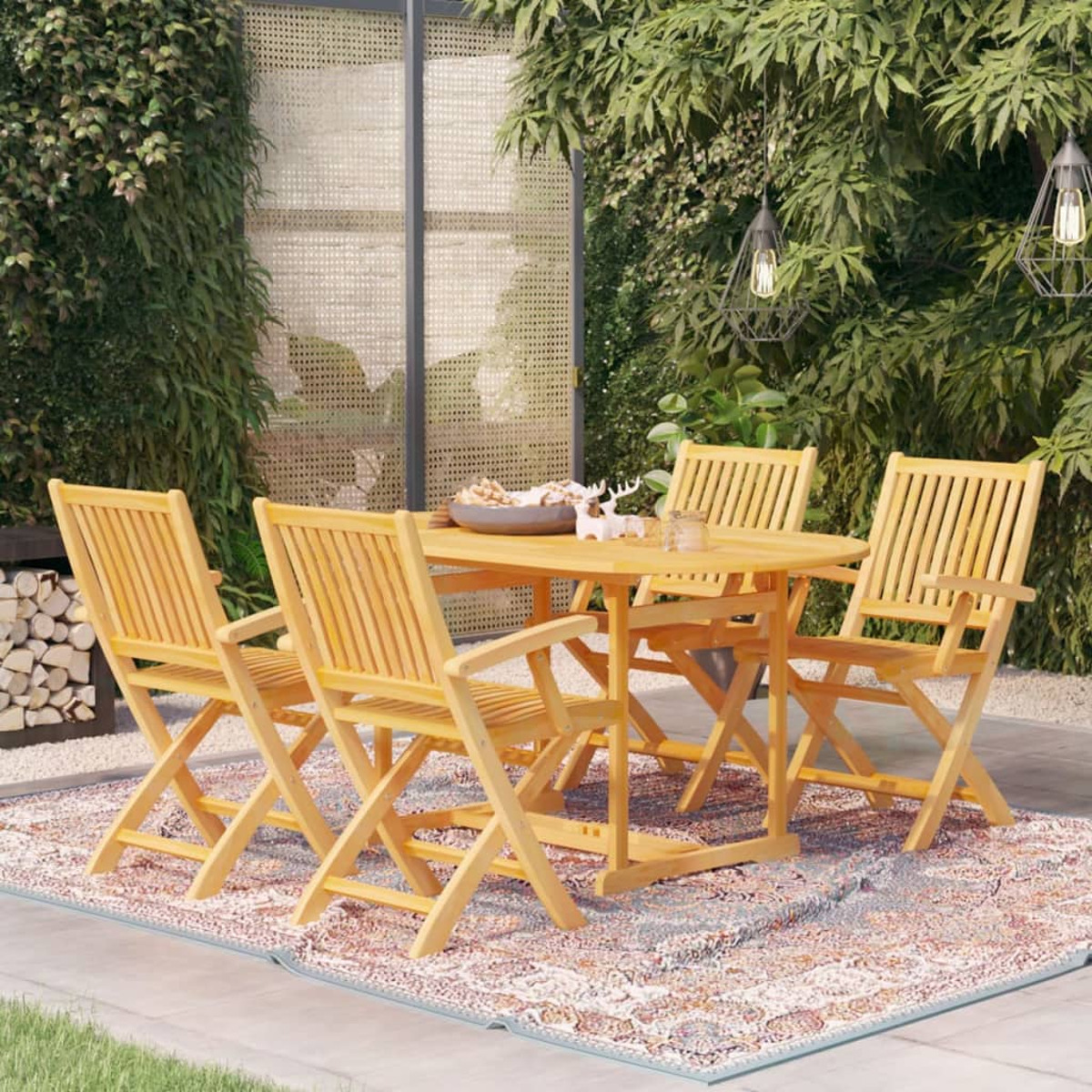 Holz-Terrassenset: Tisch und vier Klappstühle auf einem gemusterten Teppich, Gartenhintergrund.