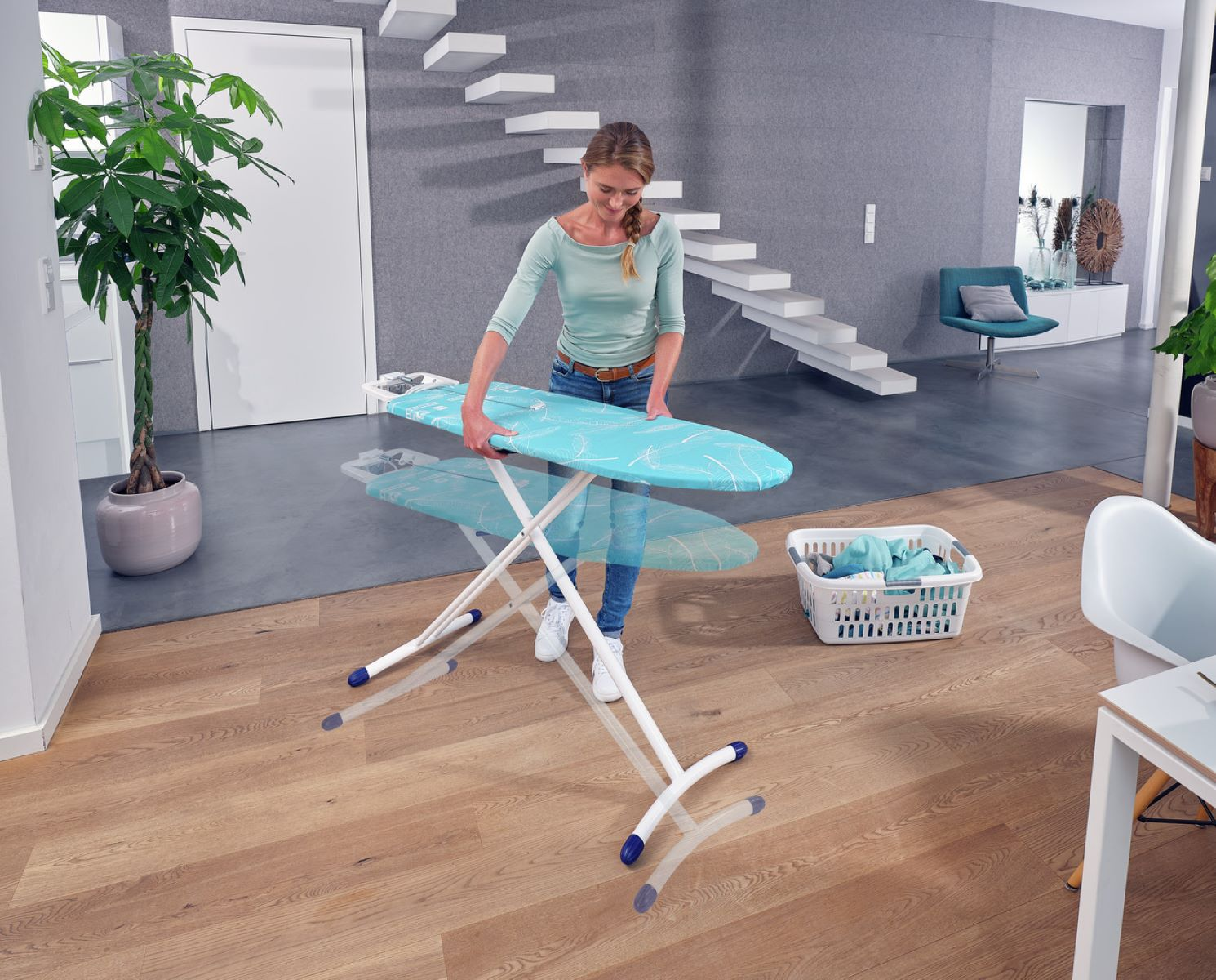 Una mujer plancha ropa en una tabla de planchar plegable en una habitación clara y moderna.
