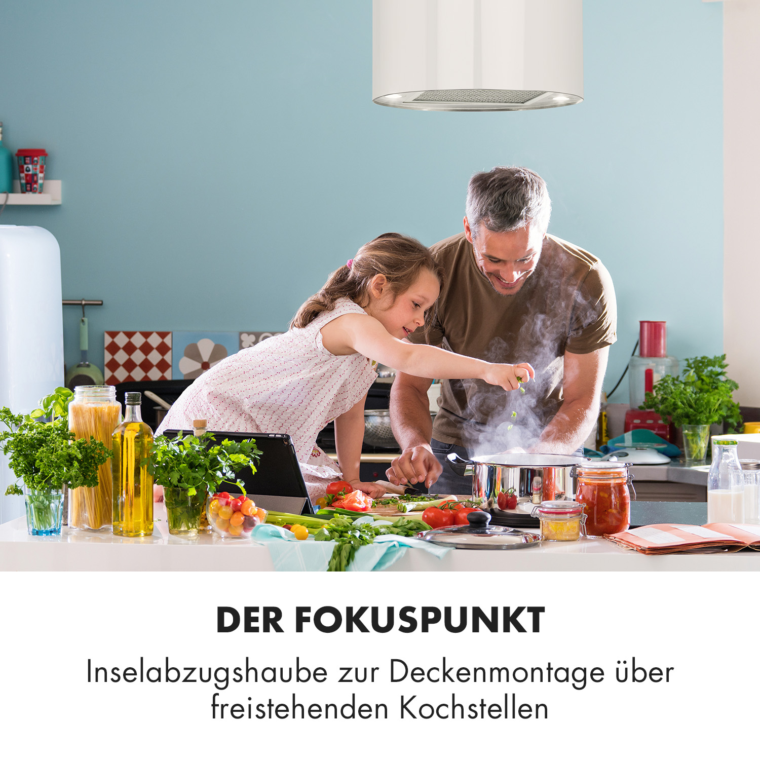 Un padre e una figlia cucinano in cucina. Il testo recita DER FOKUSUPUNKT, Inselabzugshaube.