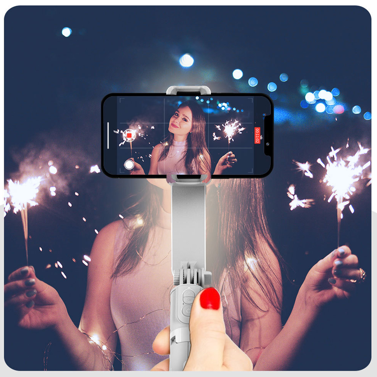Eine Person hält ein Telefon mit Selfie-Stick, Feuerwerk im Hintergrund.