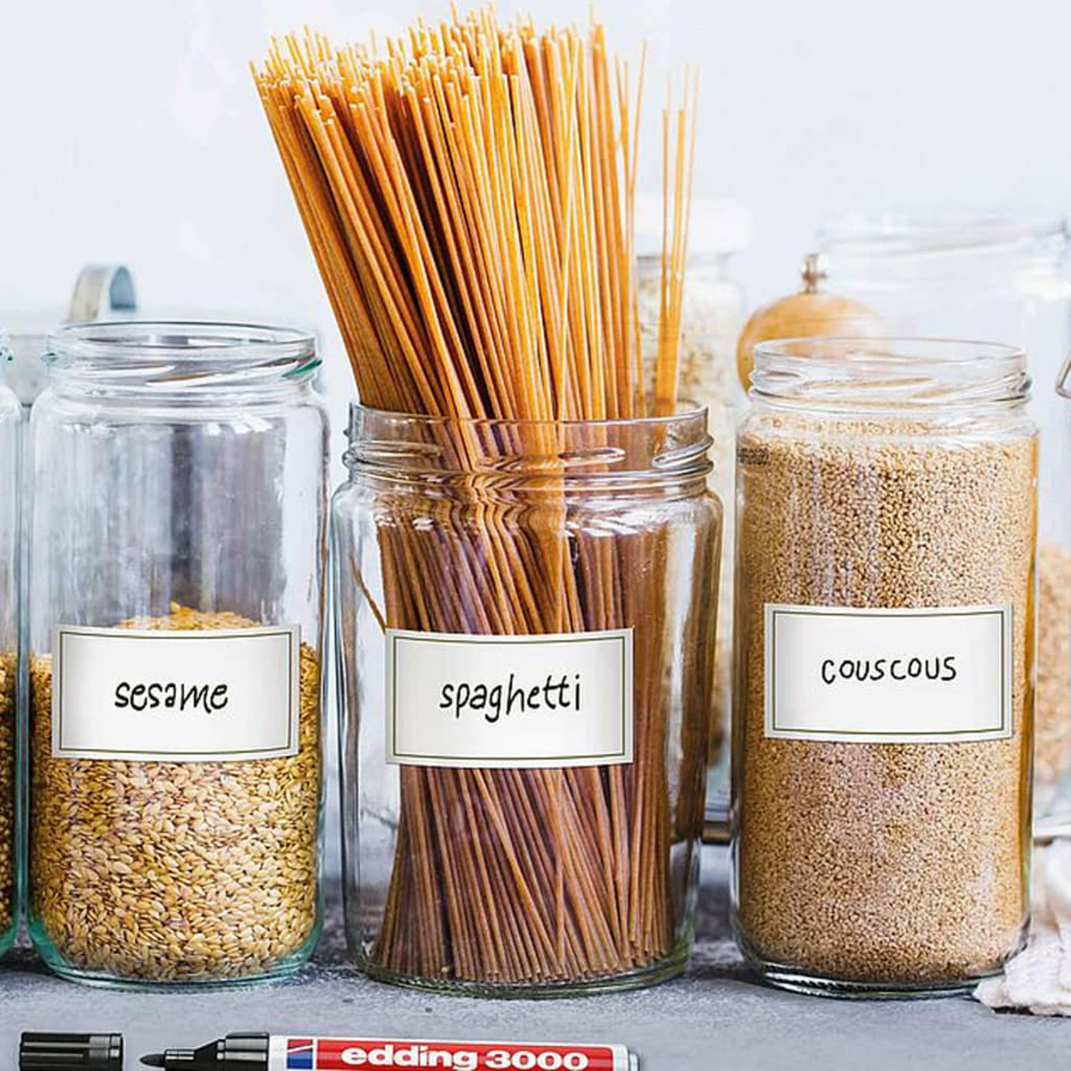 Glasbehälter mit Etiketten: Sesam, Spaghetti und Couscous. Spaghetti stehen im Mittelpunkt.
