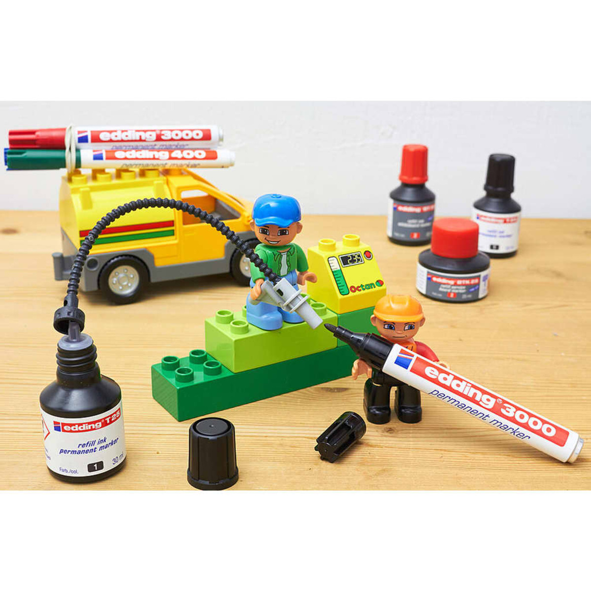Spielzeugszene mit Legosteinen, Markern und einem Spielzeug-LKW. Vordergrund hat Marker, Tinte und Figuren.